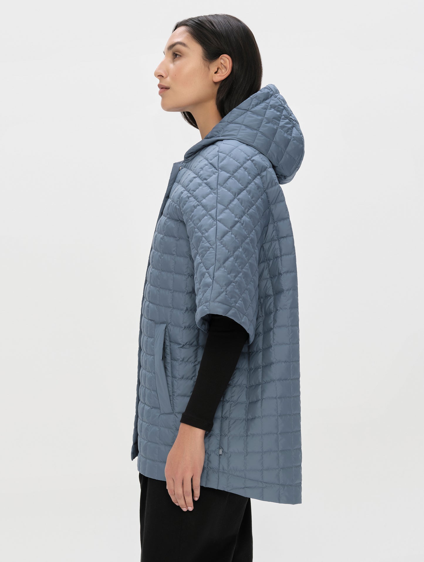 Side profile upper-body view of woman wearing the Bardo Hooded Poncho in Portal Blue from AETHER Apparel.