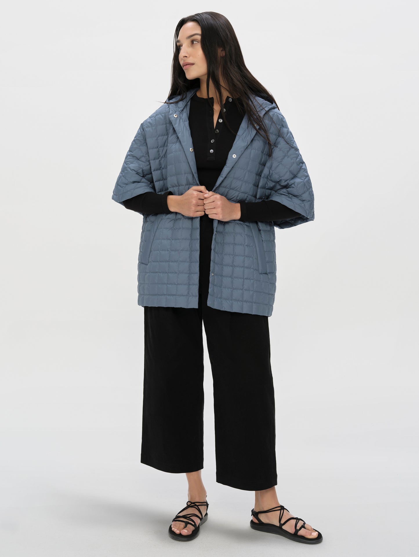 Front, angled full-body view of woman wearing the Bardo Hooded Poncho in Portal Blue from AETHER Apparel.