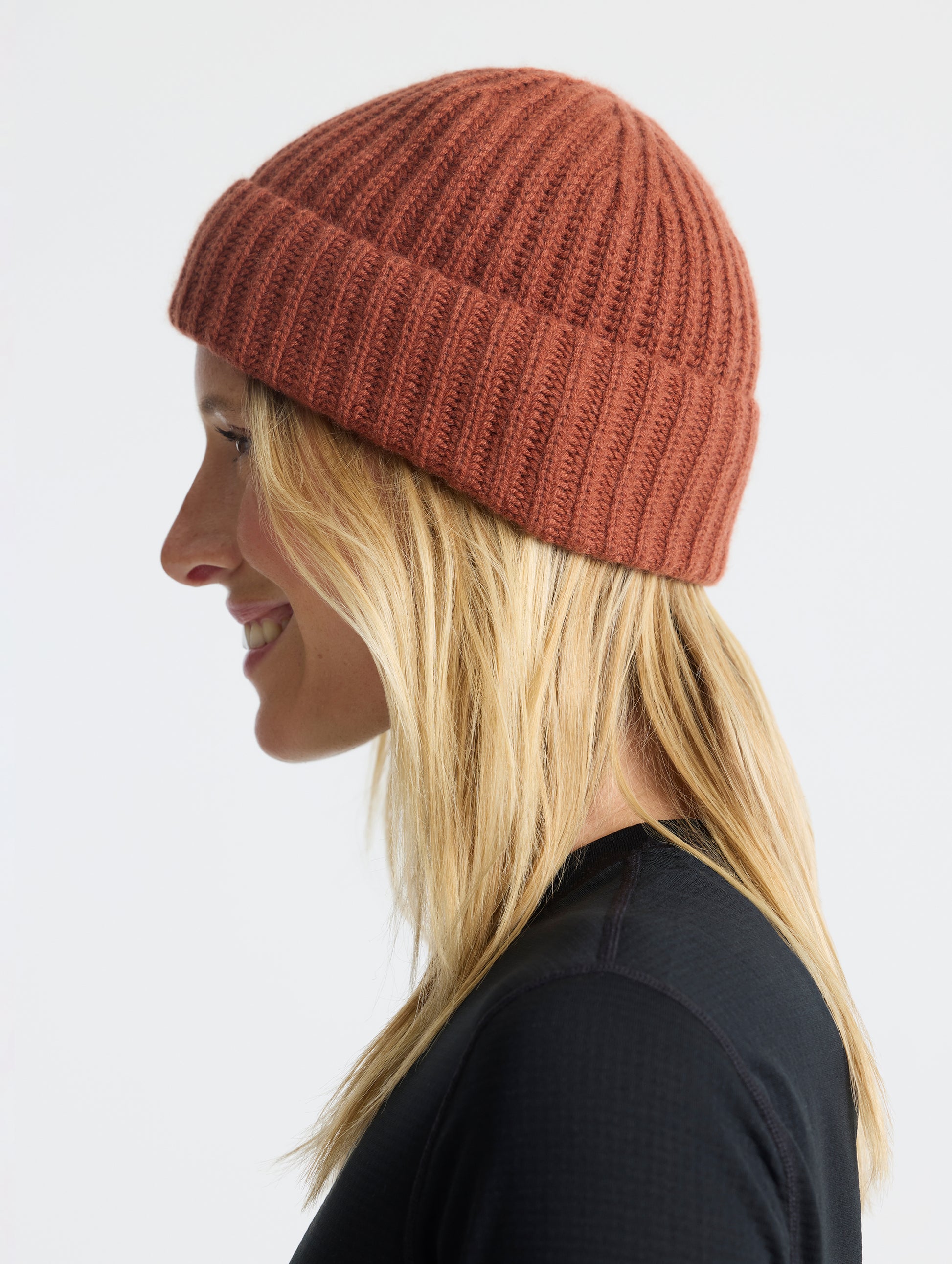 Side profile view of woman wearing the Cashmere Hat in Redwood Rust from AETHER Apparel. 