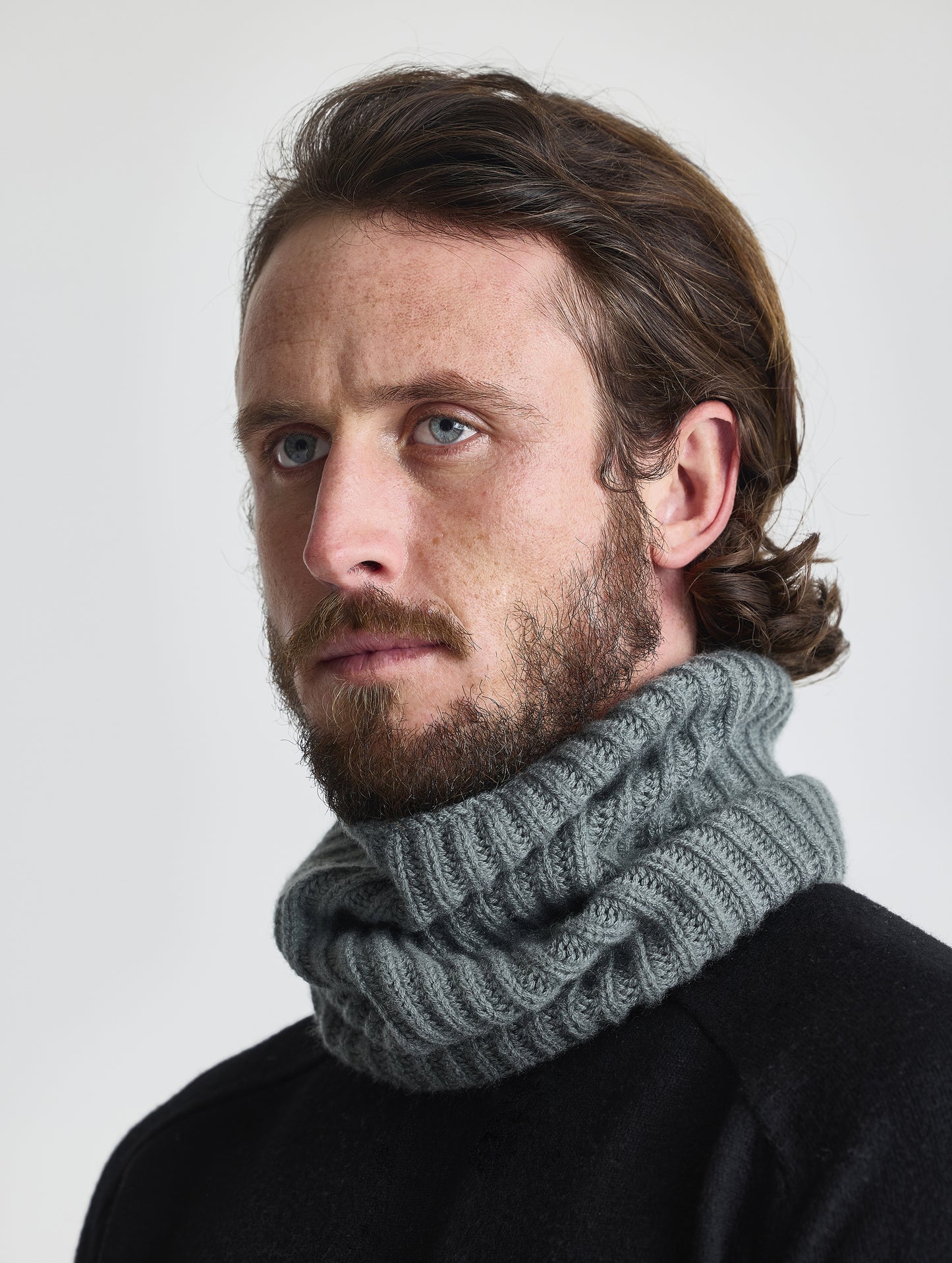 Front right angled view of man wearing the Cashmere Neck Gaiter in Gunmetal from AETHER Apparel. 