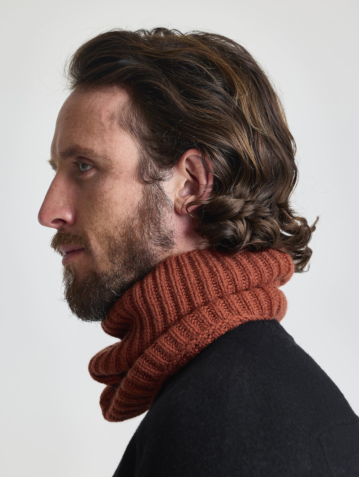 Side profile view of man wearing the Cashmere Neck Gaiter in Redwood Rust from AETHER Apparel. 