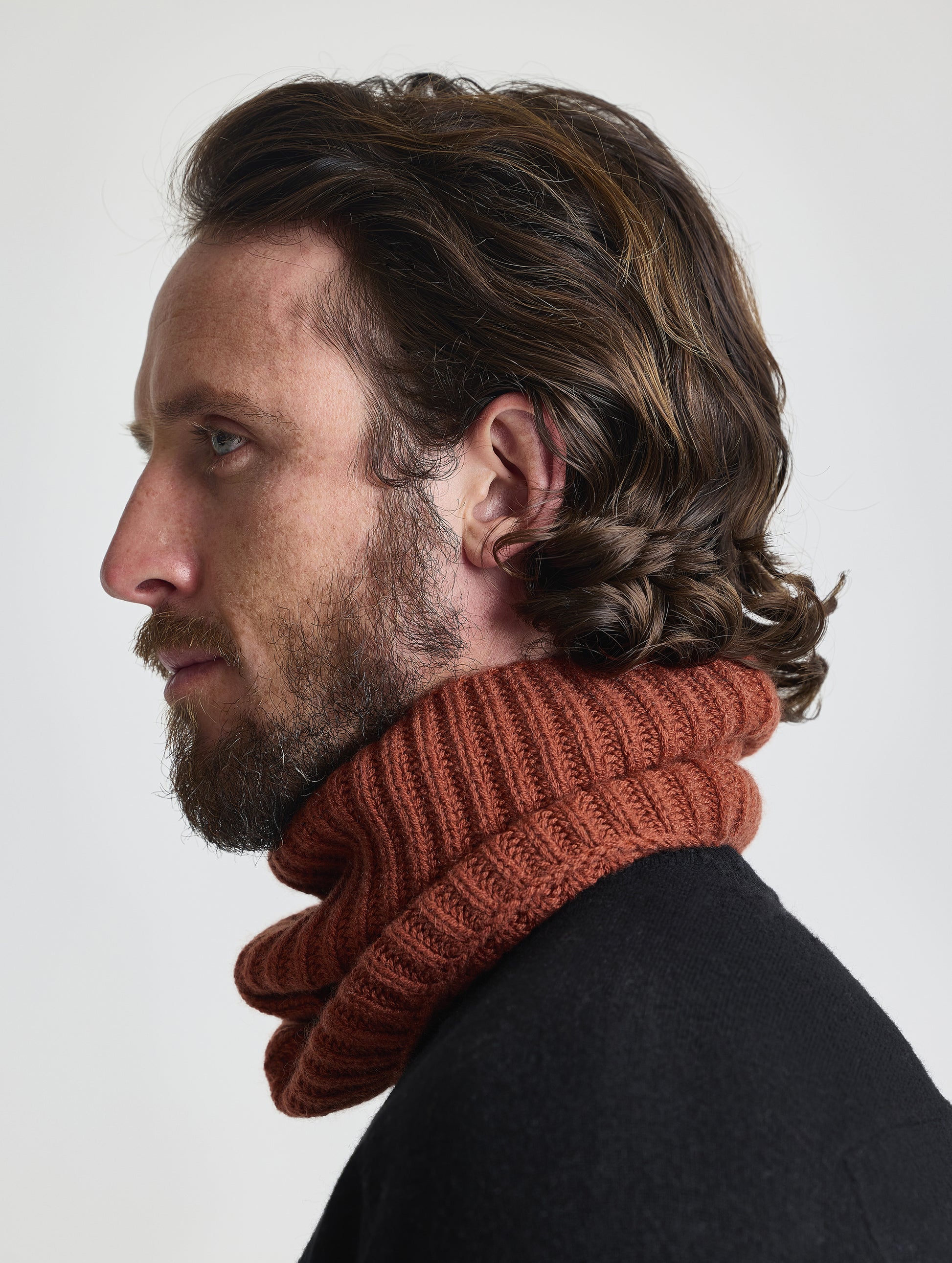 Side profile view of man wearing the Cashmere Neck Gaiter in Redwood Rust from AETHER Apparel. 