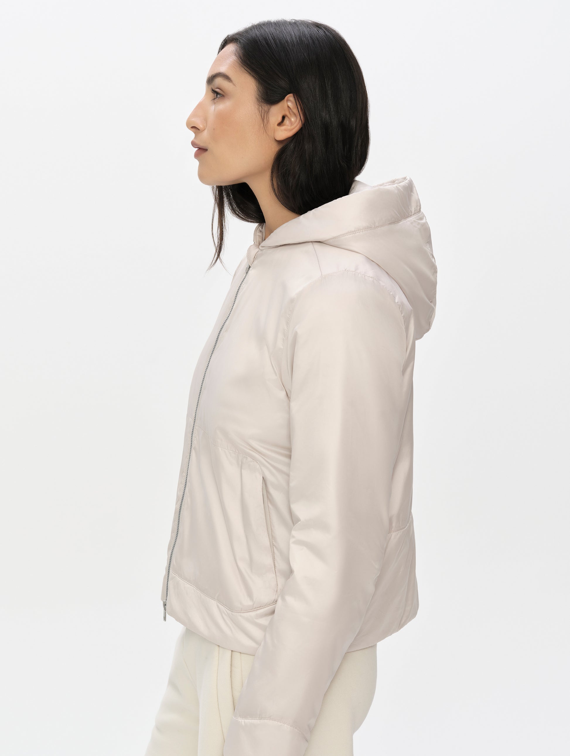 Side, profile upper-body view of woman wearing the Celeste Eco Insulated Vest in Bone from AETHER Apparel.