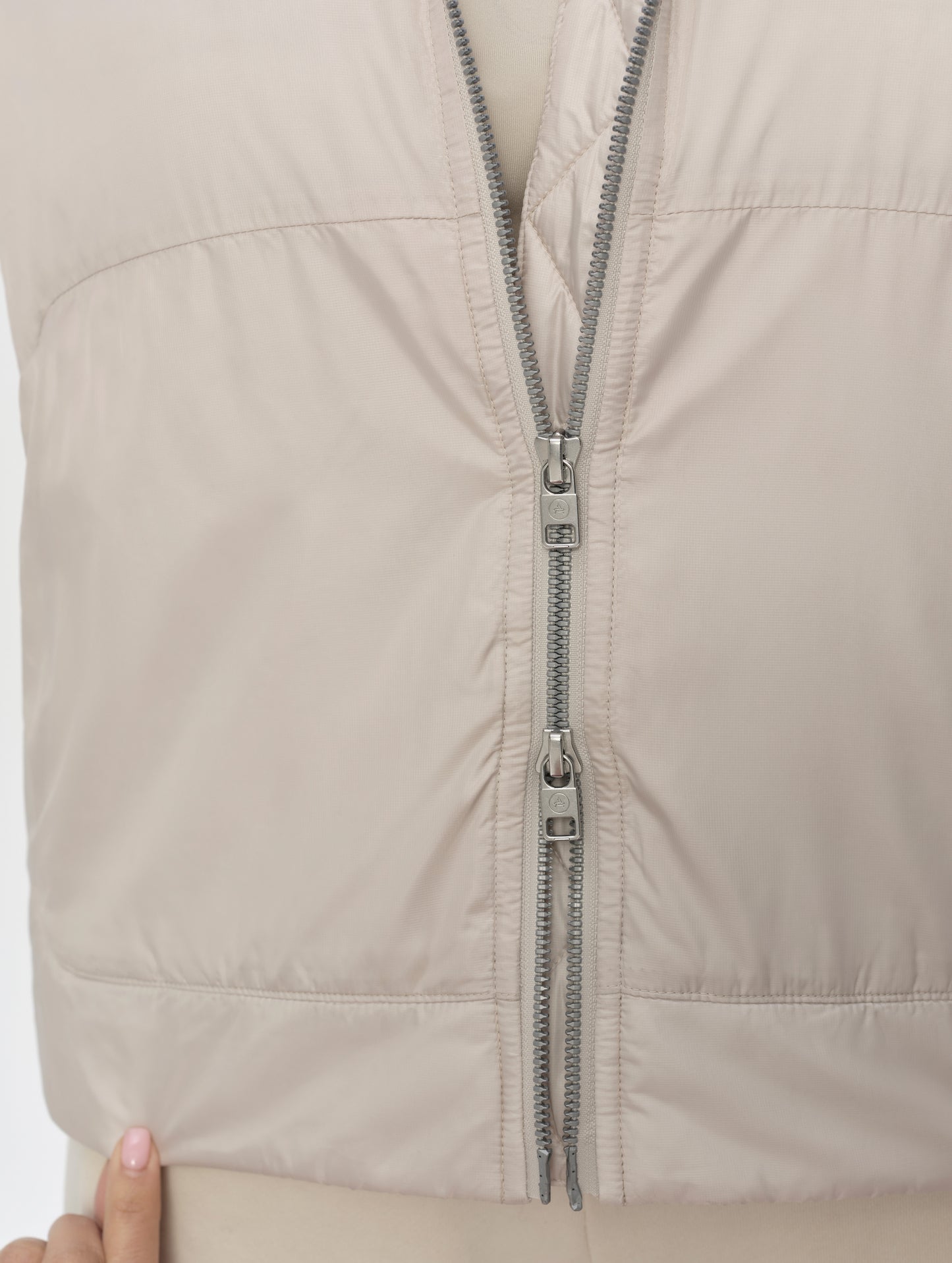 Closeup detailed view of the two-way center-front zipper on the Celeste Eco Insulated Hoodie in Bone from AETHER Apparel.