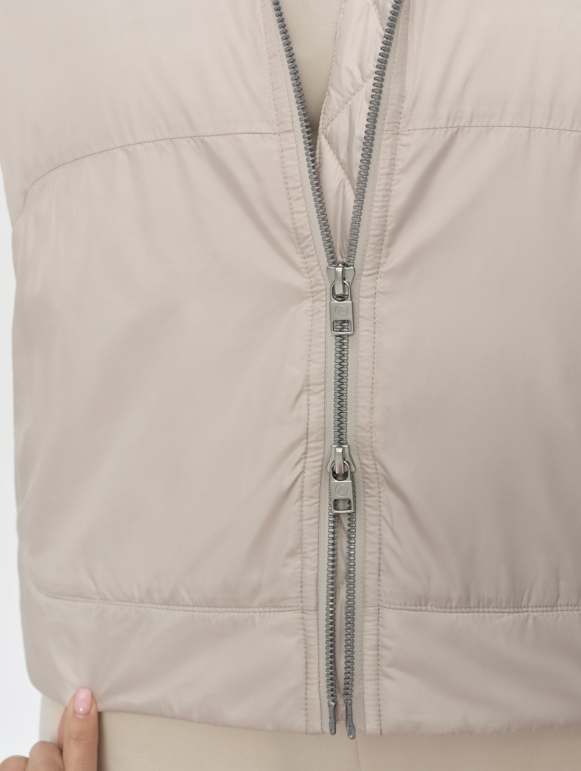 Closeup detailed view of the two-way center-front zipper on the Celeste Eco Insulated Hoodie in Bone from AETHER Apparel.