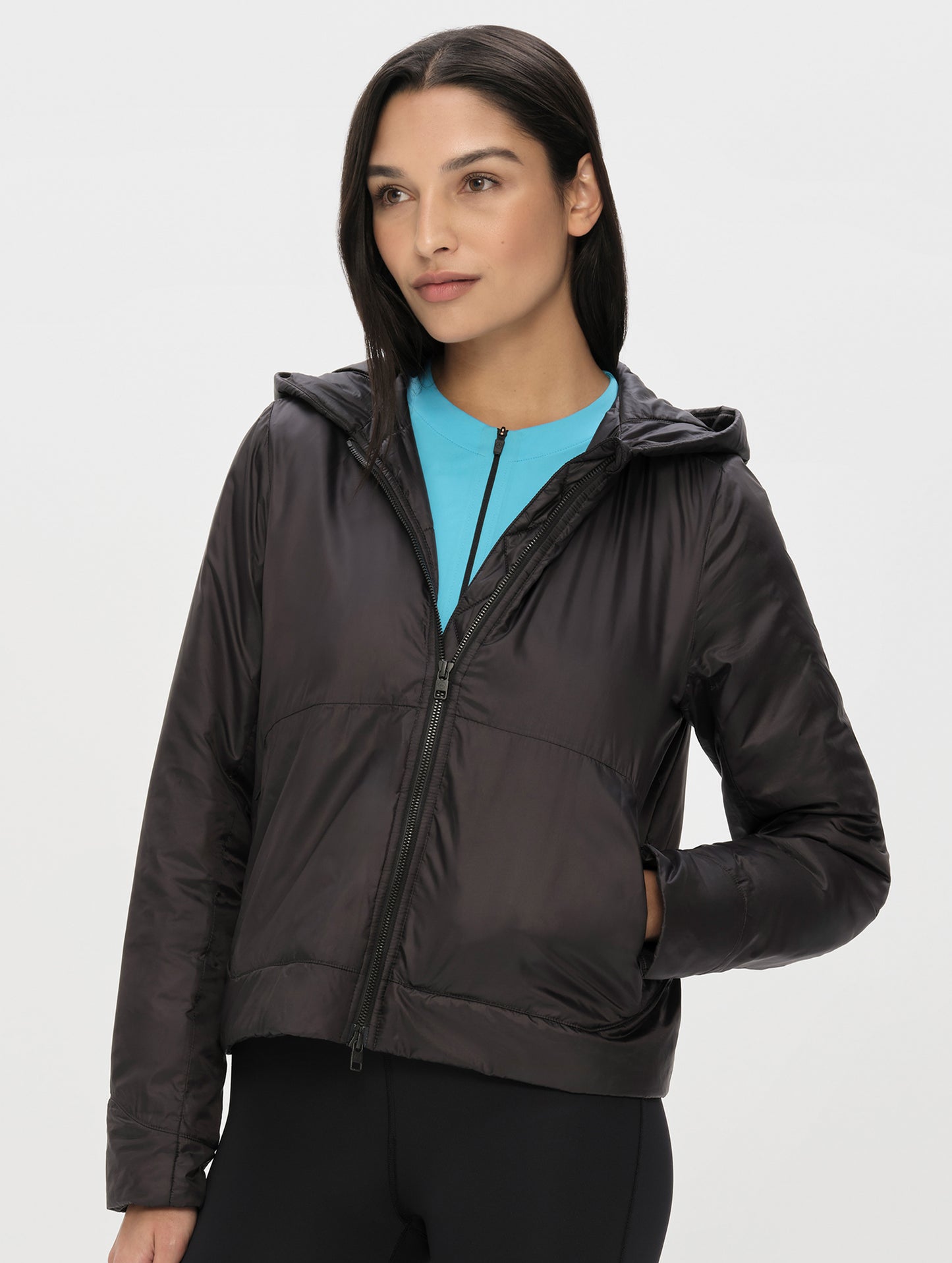 Front upper-body view of woman wearing the Celeste Eco Insulated Hoodie in Onyx Black from AETHER Apparel.