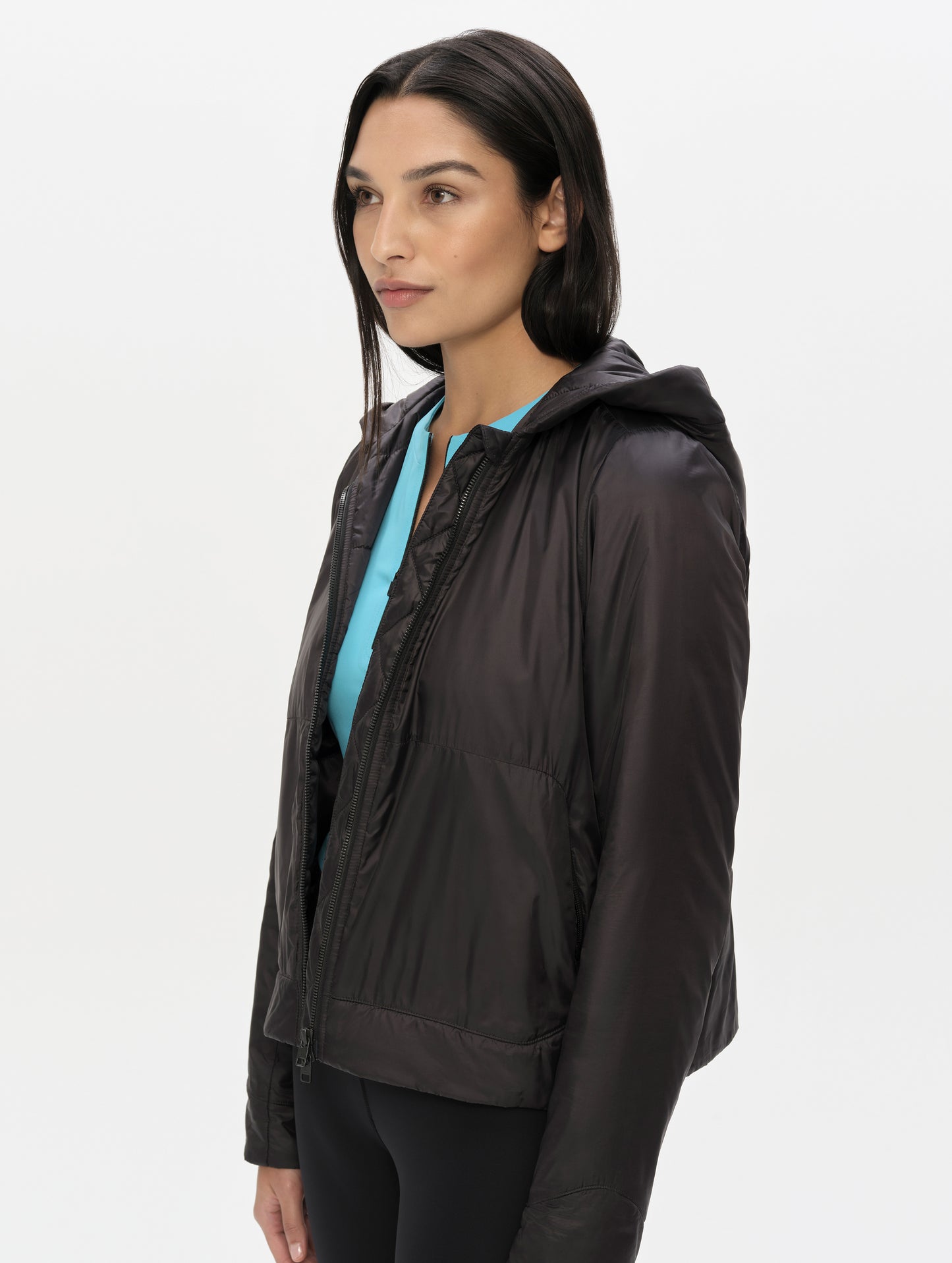 Front, angled upper-body view of woman wearing the Celeste Eco Insulated Hoodie in Onyx Black from AETHER Apparel.