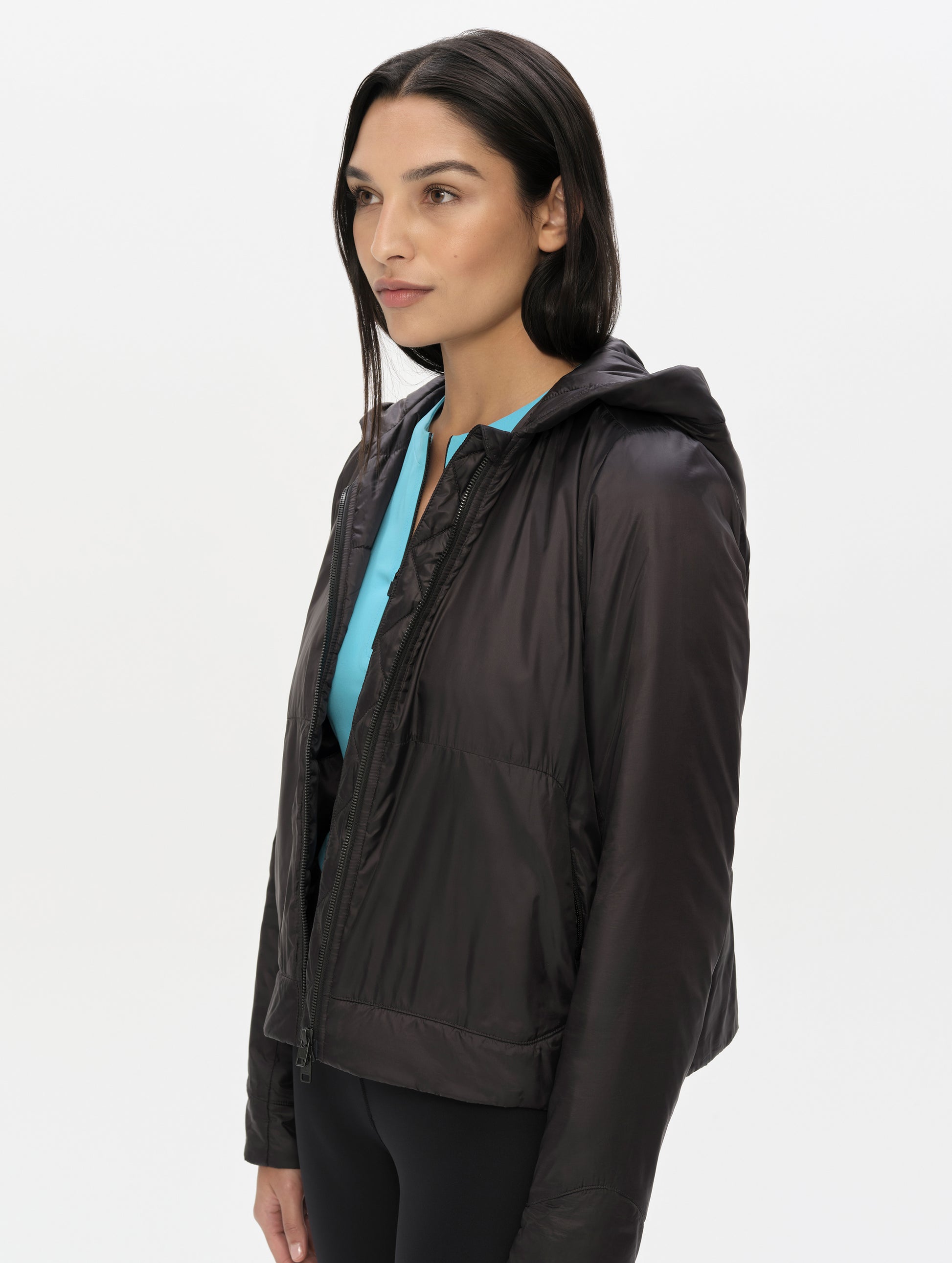 Front, angled upper-body view of woman wearing the Celeste Eco Insulated Hoodie in Onyx Black from AETHER Apparel.