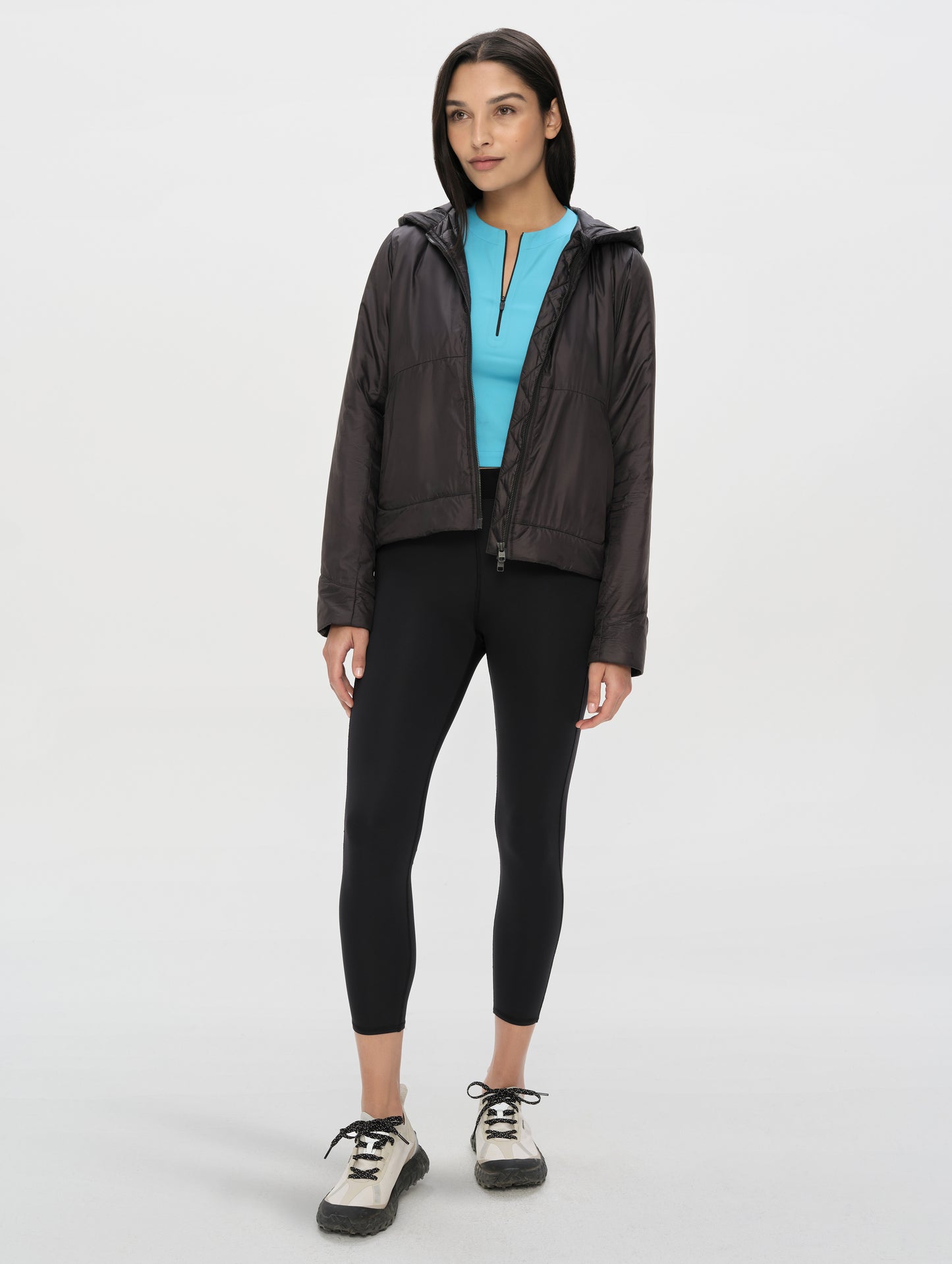 Front full-body view of woman wearing the Celeste Eco Insulated Hoodie in Onyx Black from AETHER Apparel.