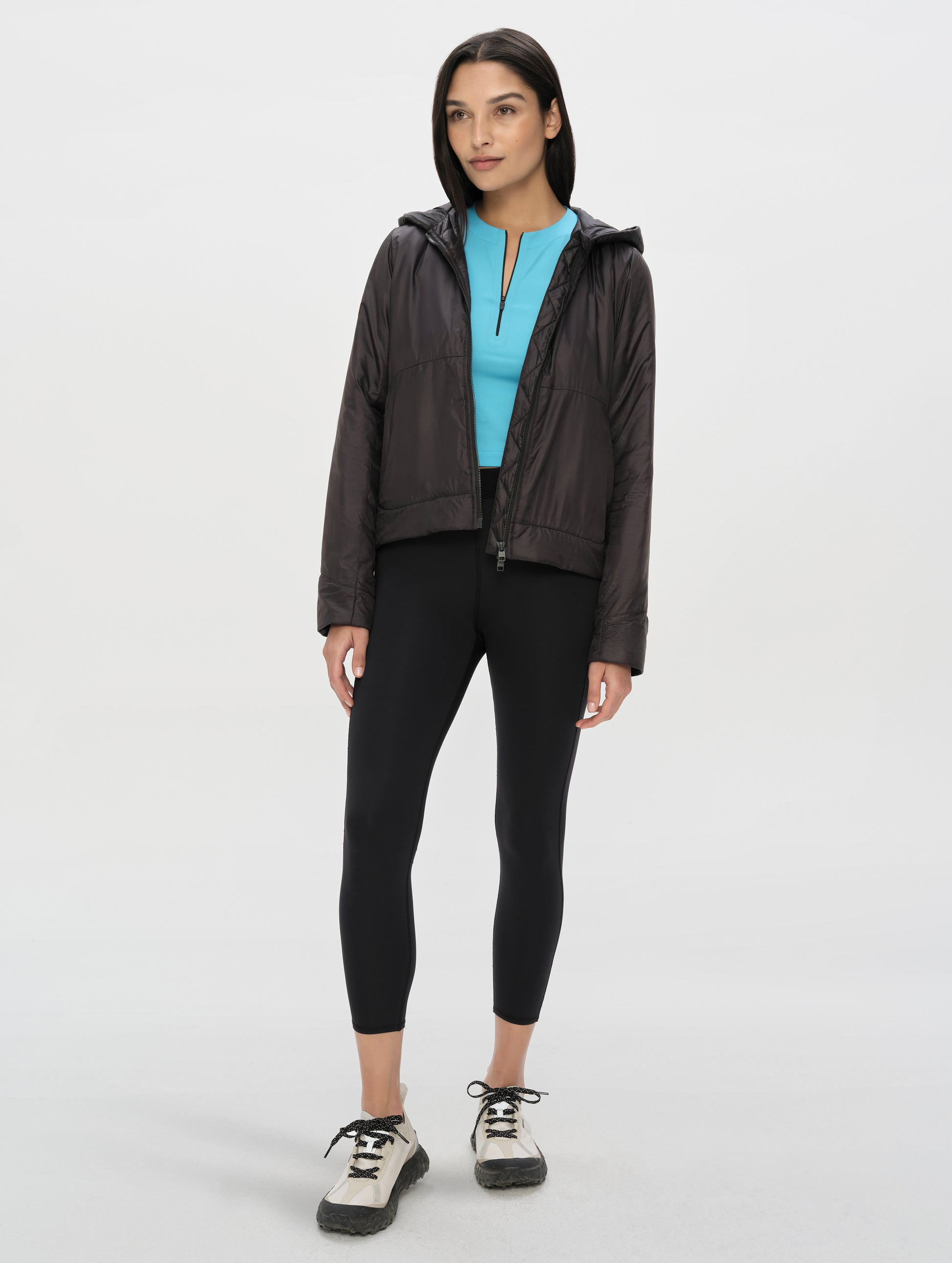 Front full-body view of woman wearing the Celeste Eco Insulated Hoodie in Onyx Black from AETHER Apparel.