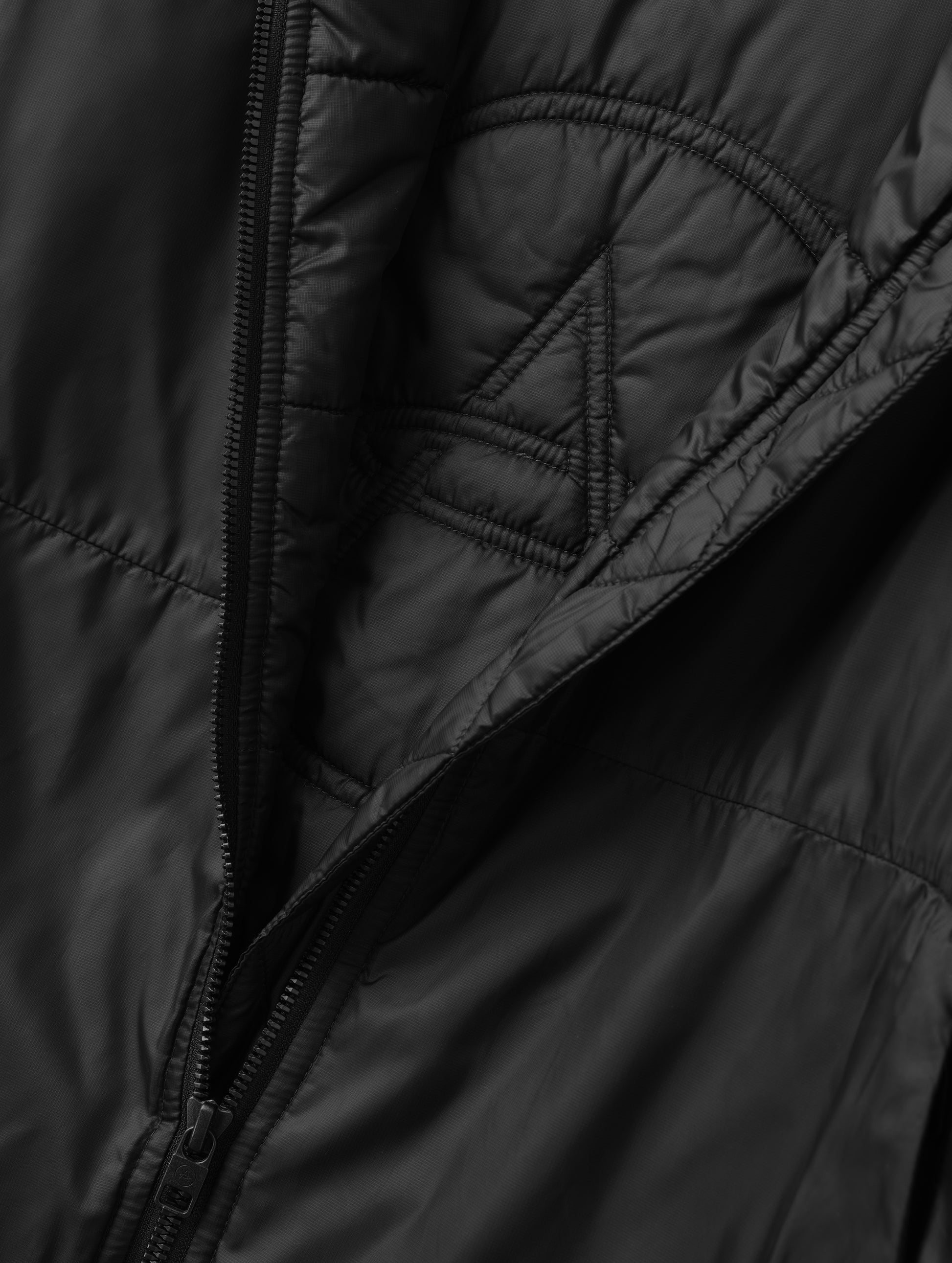Closeup detailed view of the custom AETHER logo quilting on the interior of the Celeste Eco Insulated Hoodie in Onyx Black from AETHER Apparel.
