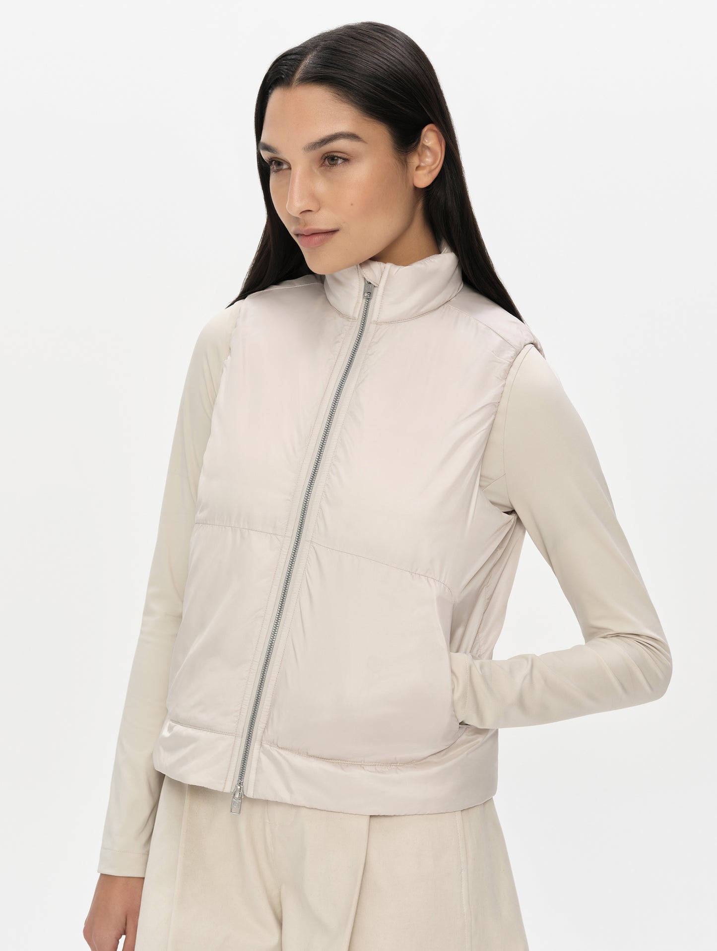 Front, angled upper-body view of woman wearing the Celeste Eco Insulated Vest in Bone from AETHER Apparel fully zipped up.