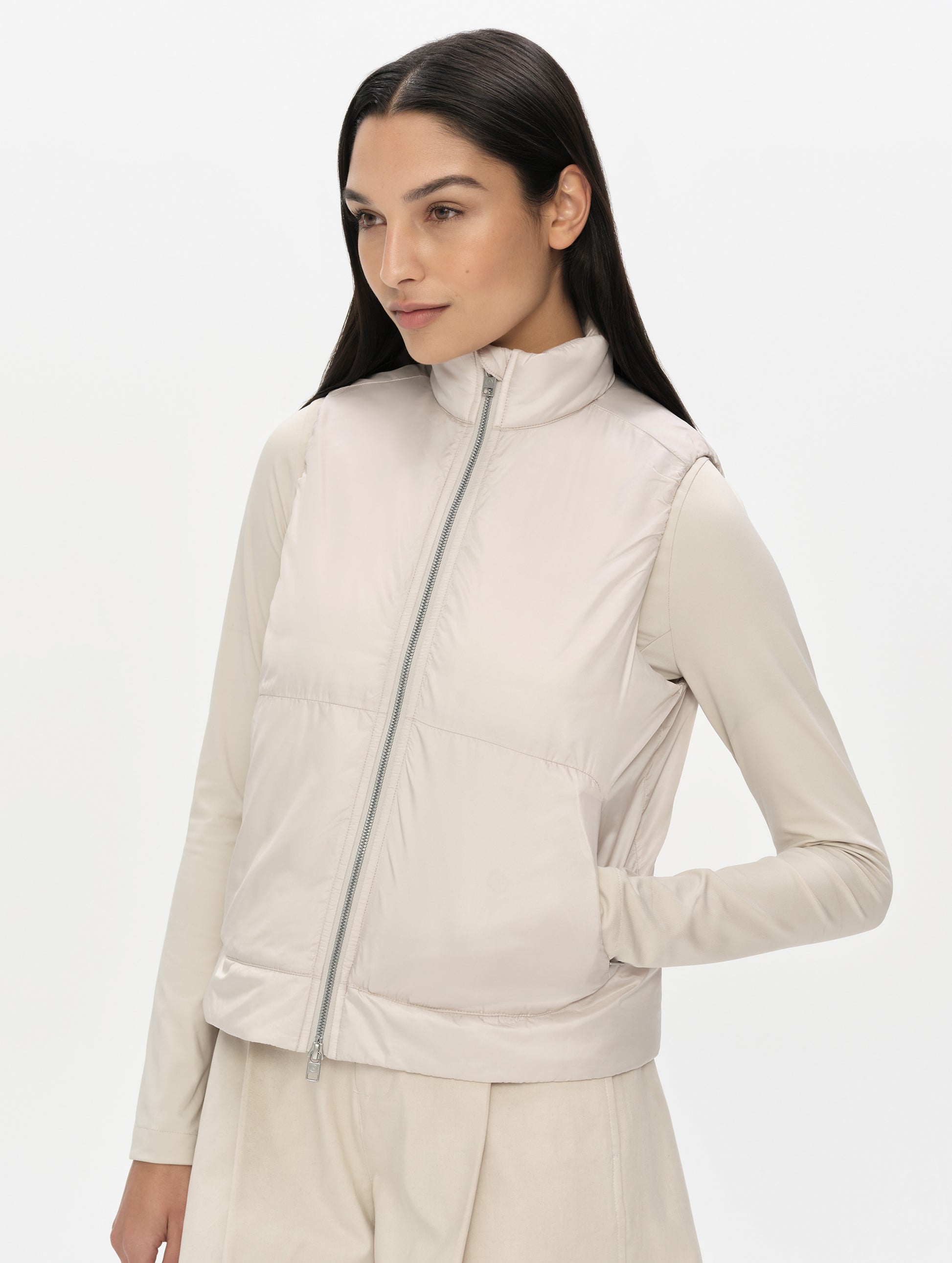 Front, angled upper-body view of woman wearing the Celeste Eco Insulated Vest in Bone from AETHER Apparel fully zipped up.