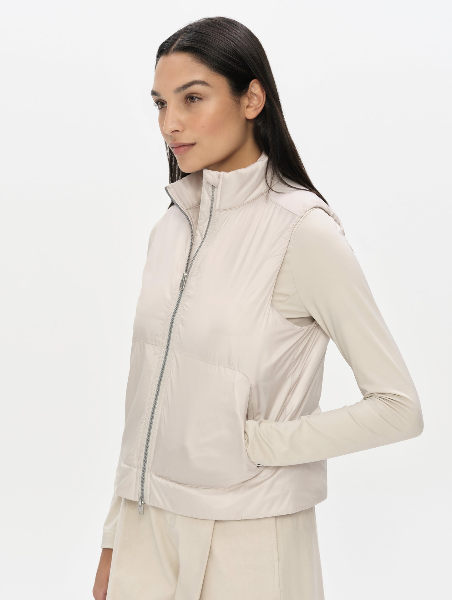 Front, angled upper-body view of woman wearing the Celeste Eco Insulated Vest in Bone from AETHER Apparel with collar unzipped. 