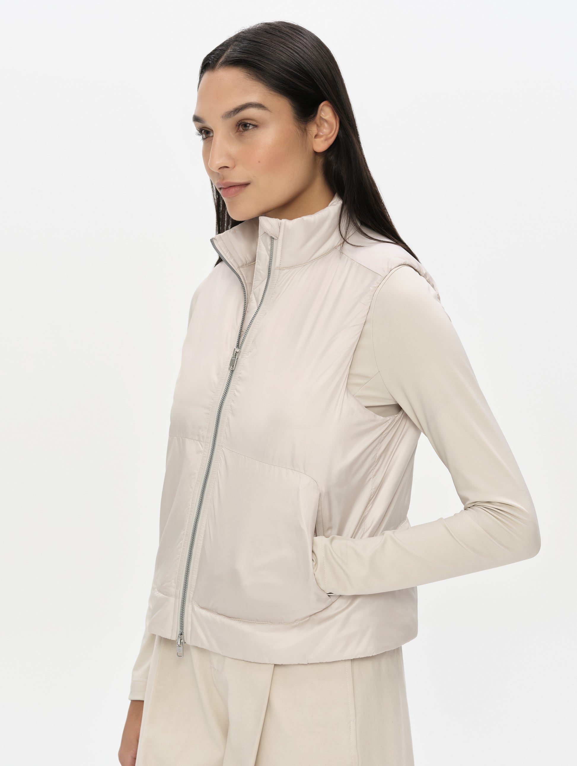 Front, angled upper-body view of woman wearing the Celeste Eco Insulated Vest in Bone from AETHER Apparel with collar unzipped. 