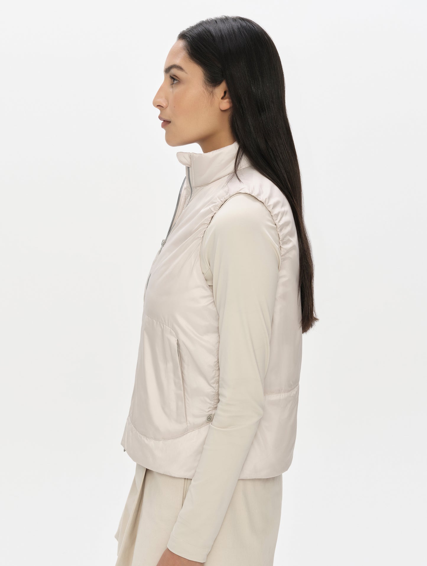 Side profile, upper-body view of woman wearing the Celeste Eco Insulated Vest in Bone from AETHER Apparel.
