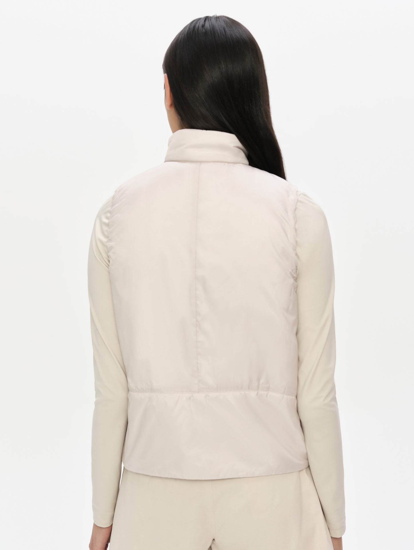 Rear upper-body view of woman wearing the Celeste Eco Insulated Vest in Bone from AETHER Apparel.