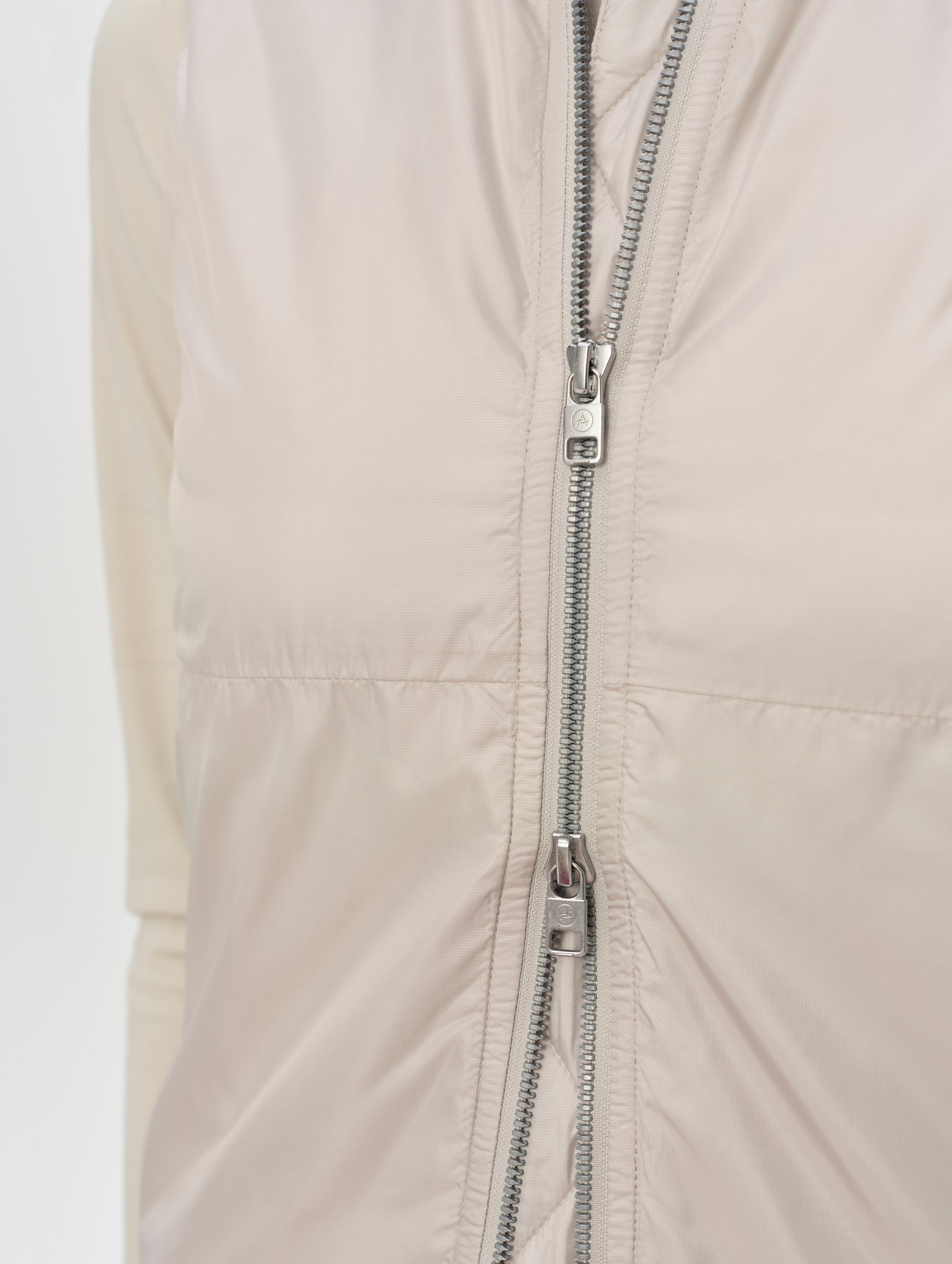 Closeup detailed view of the two-way center-front zipper on the Celeste Eco Insulated Vest in Bone from AETHER Apparel.