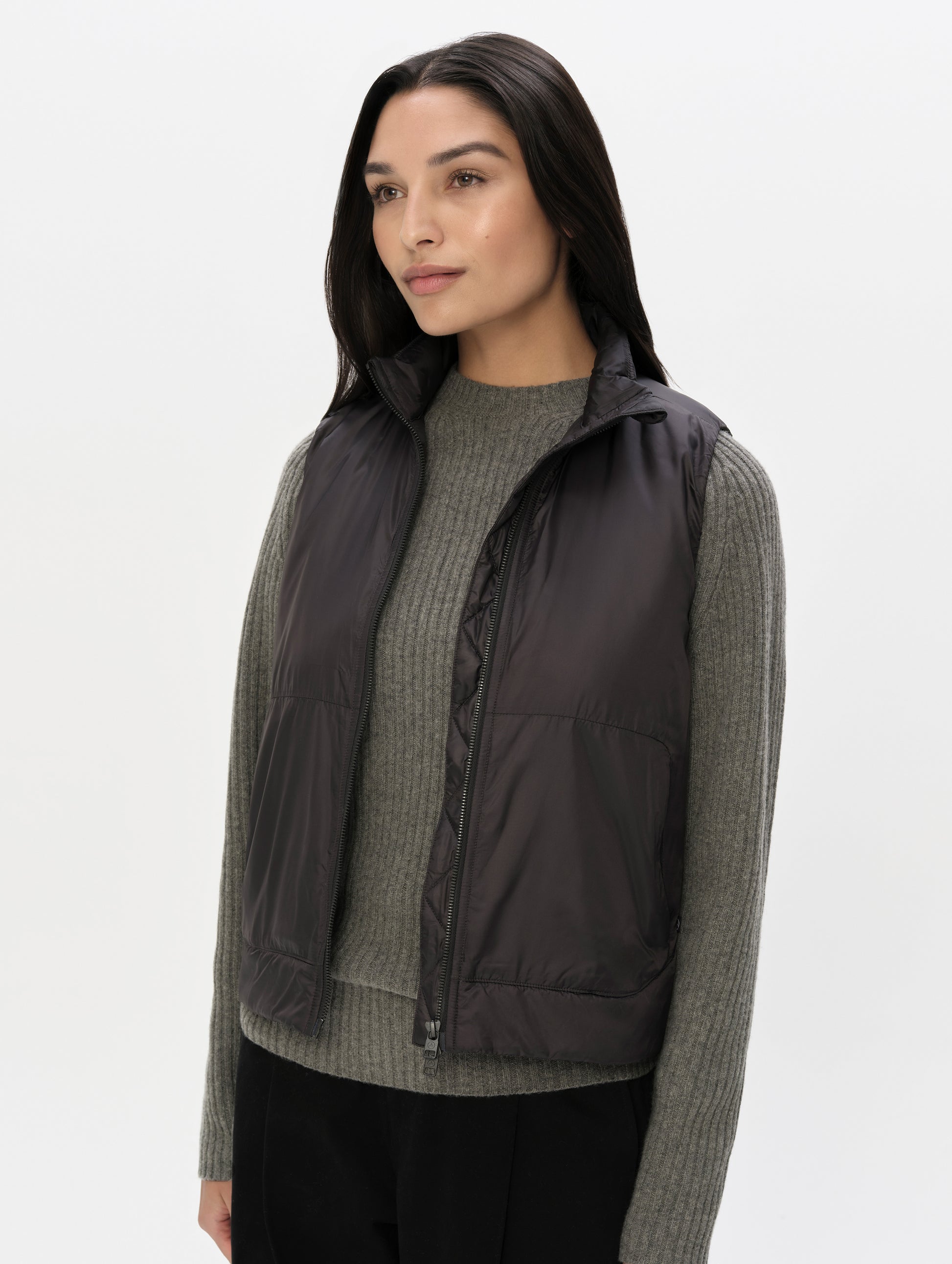 Front, angled upper-body view of woman wearing the Celeste Eco Insulated Vest in Onyx Black from AETHER Apparel.