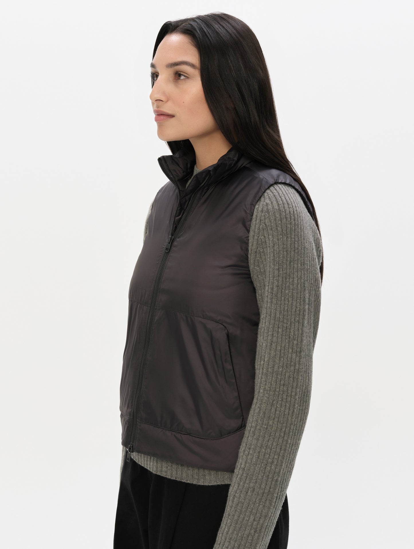 Side profile view of woman wearing the Celeste Eco Insulated Vest in Onyx Black from AETHER Apparel.