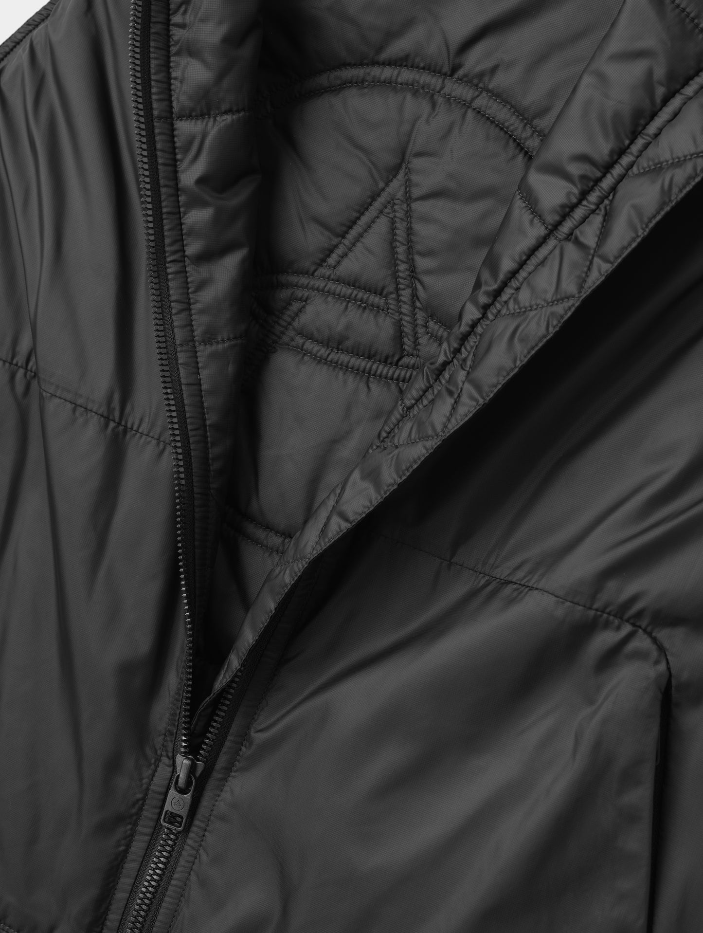 Closeup detailed view of the custom AETHER logo quilting on the interior of the Celeste Eco Insulated Vest in Onyx Black from AETHER Apparel.