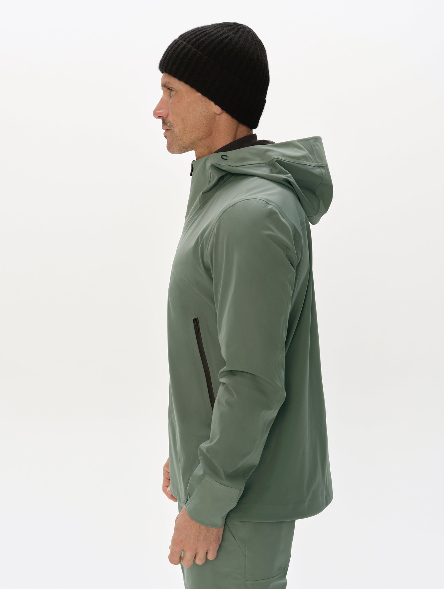 Side profile, upper-body view of man wearing the Frontier Hooded Shell Jacket in Gunmetal from AETHER Apparel.
