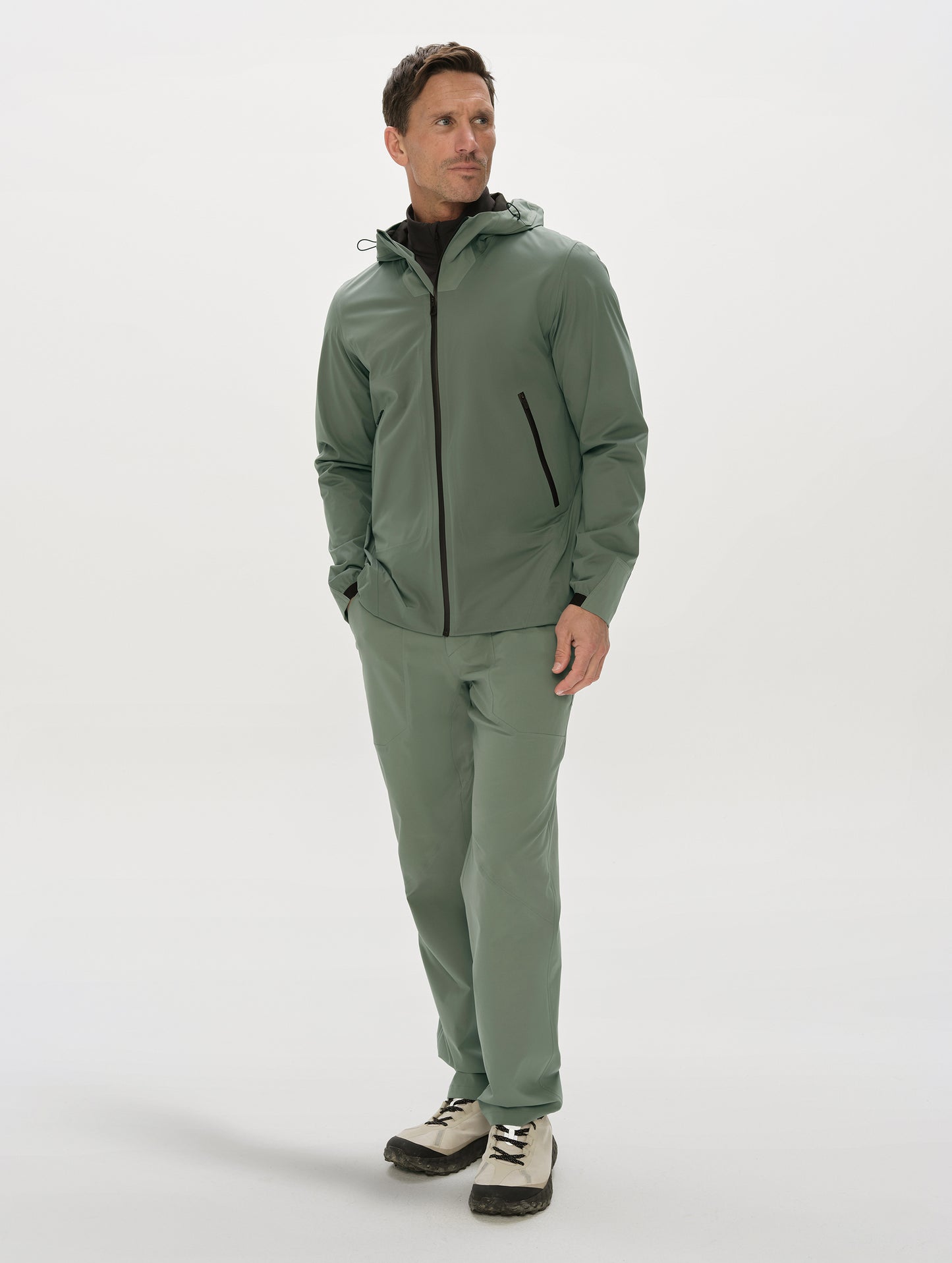Front, full-body view of man wearing the Frontier Hooded Shell Jacket in Gunmetal from AETHER Apparel.
