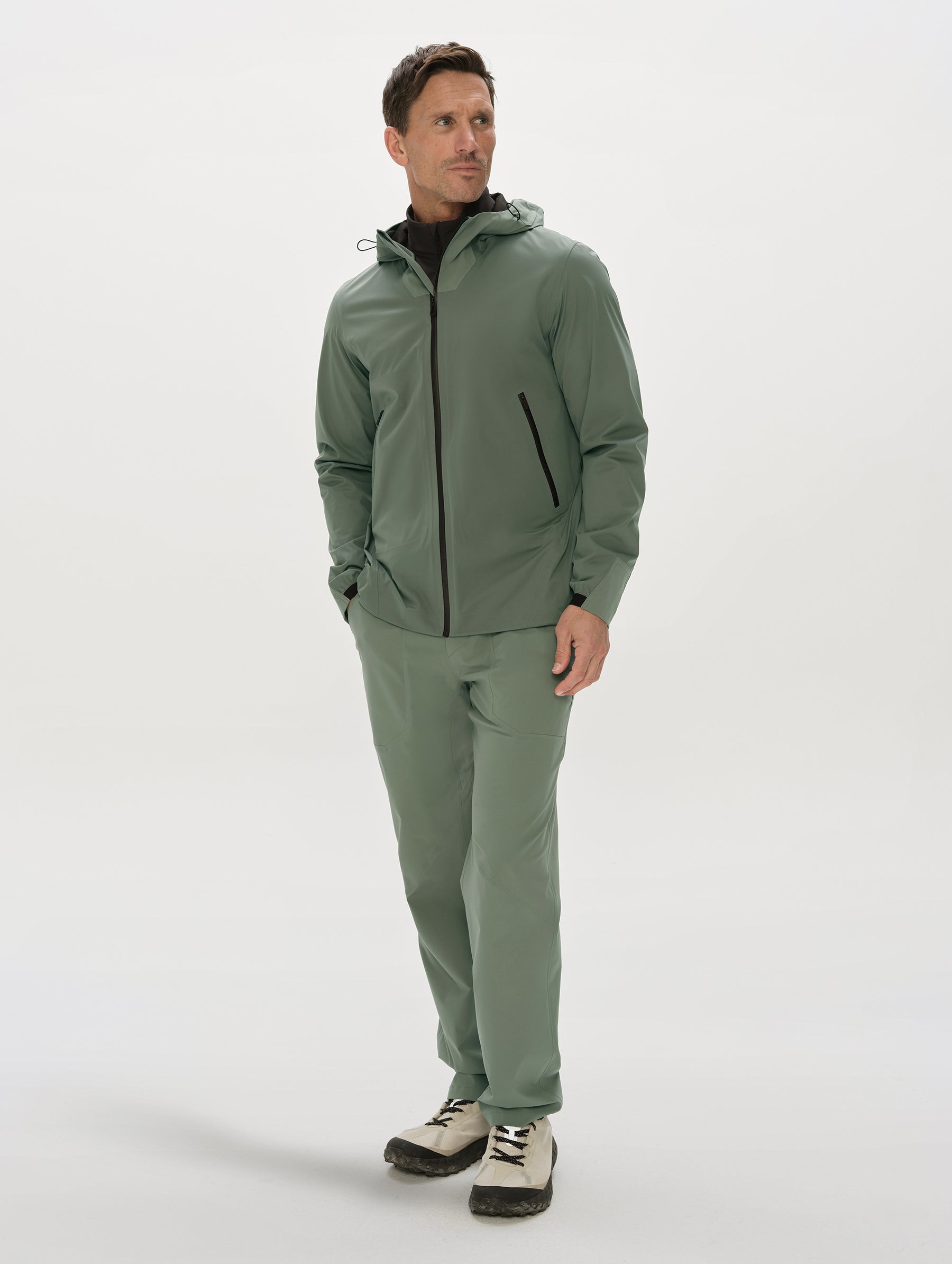 Front, full-body view of man wearing the Frontier Hooded Shell Jacket in Gunmetal from AETHER Apparel.
