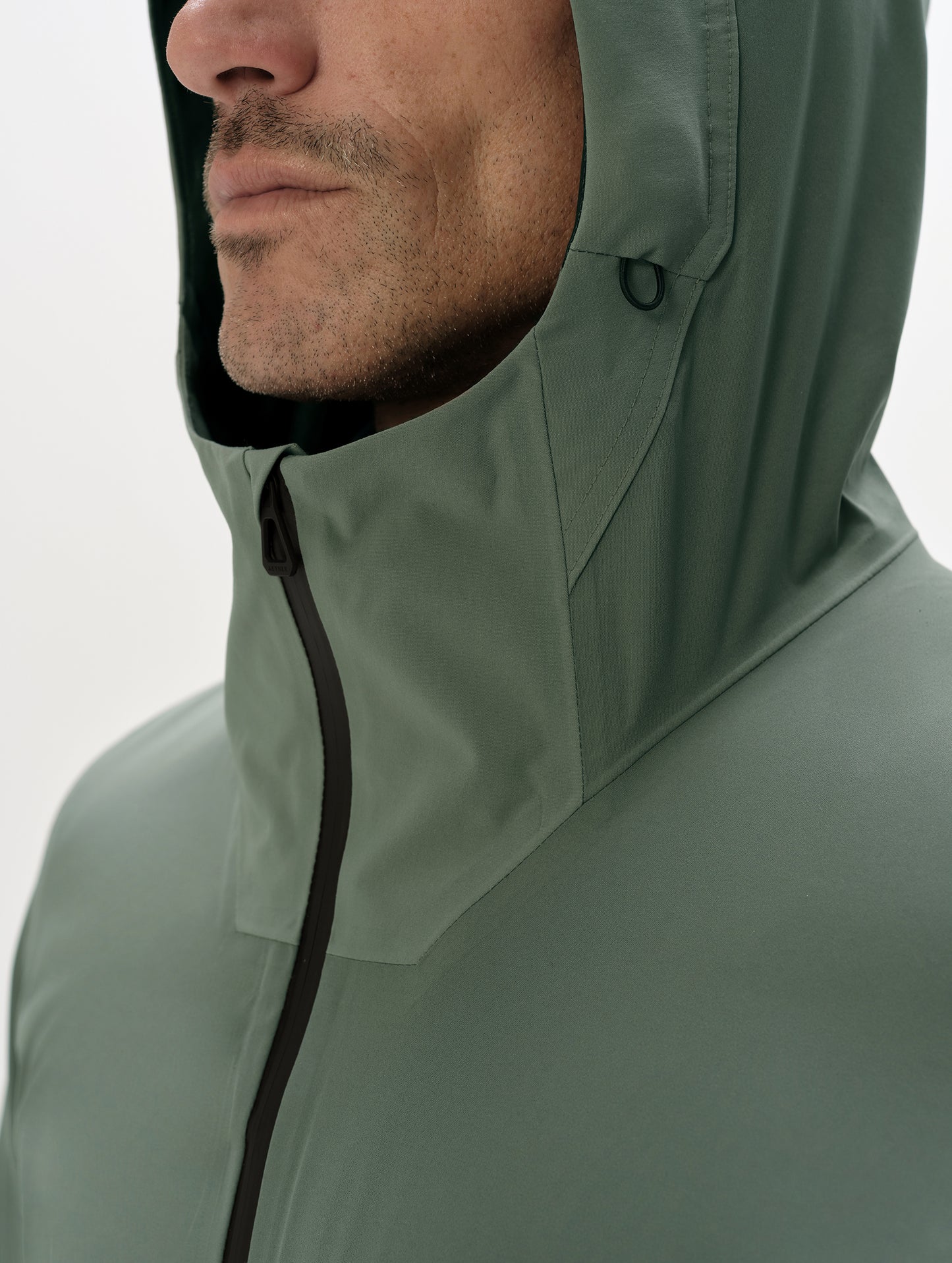 Closeup detailed view of the multi-piece hood and center-front zipper closure on the Frontier Hooded Shell Jacket in Gunmetal from AETHER Apparel.
