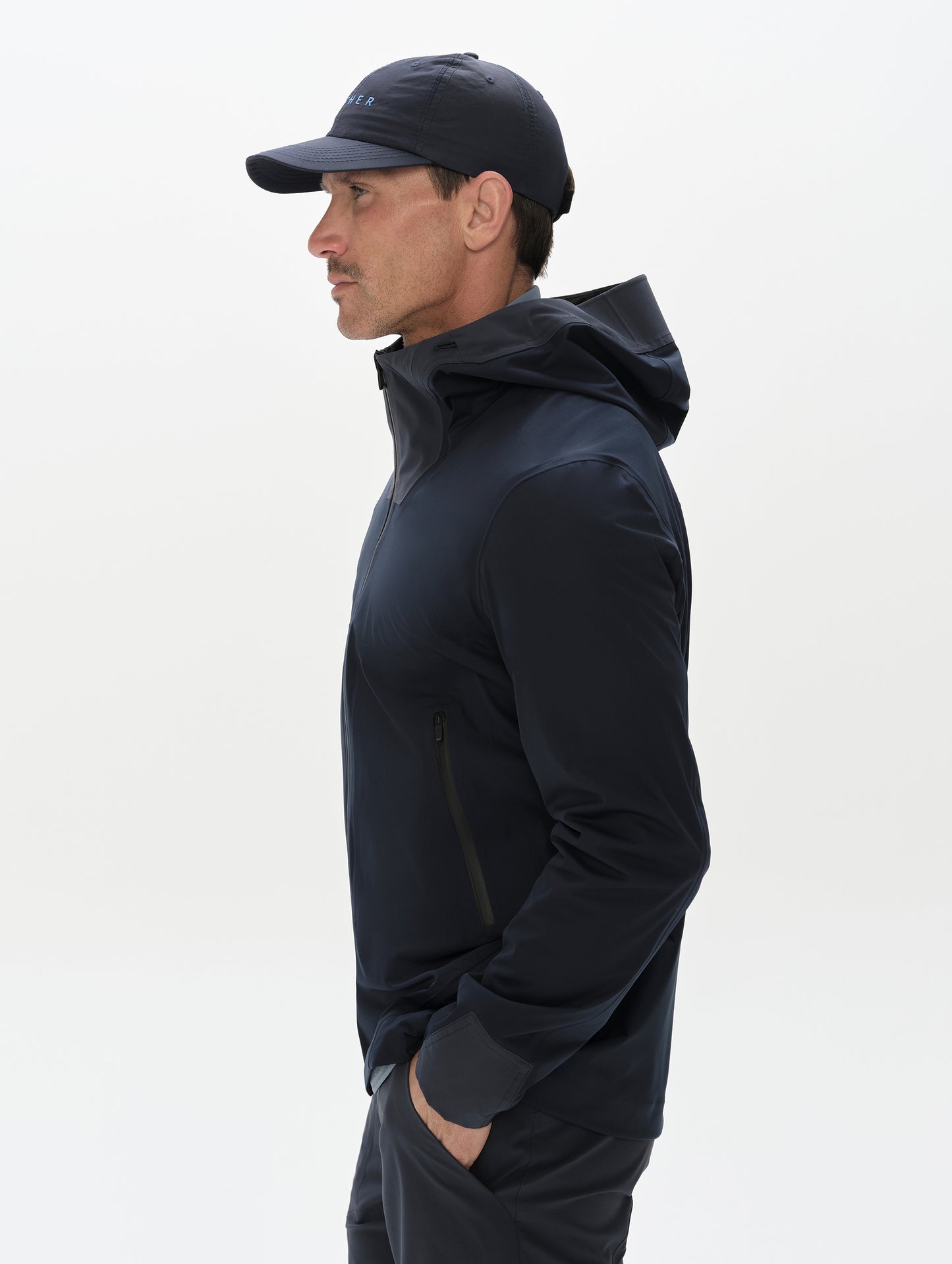 Side profile, upper-body view of man wearing the Frontier Pant in Total Eclipse dark blue from AETHER Apparel.