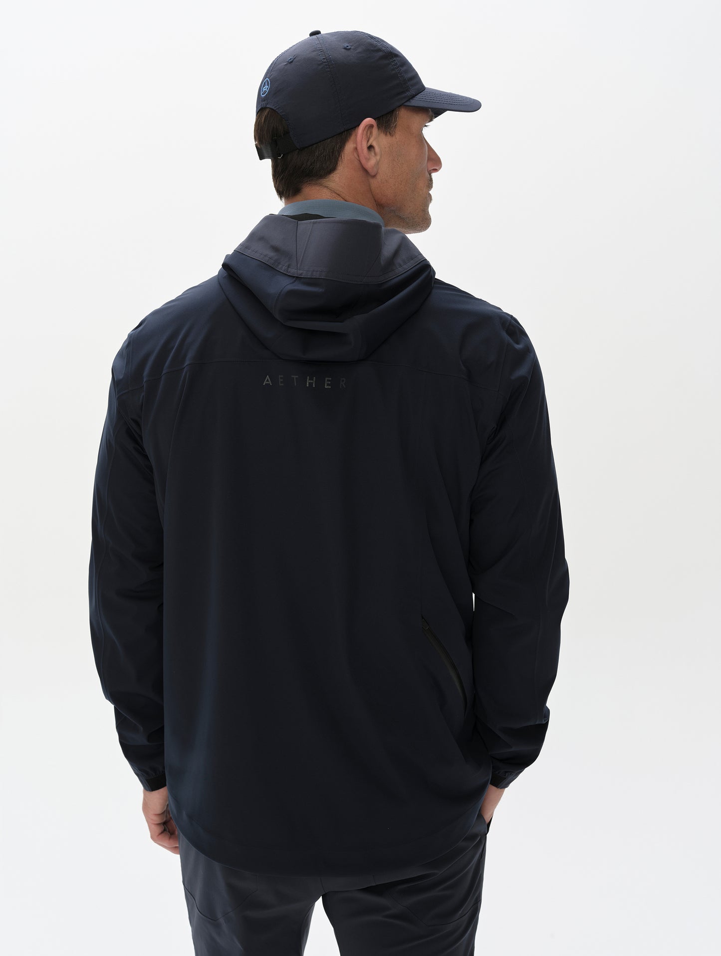 Rear, upper-body view of man wearing the Frontier Pant in Total Eclipse dark blue from AETHER Apparel.