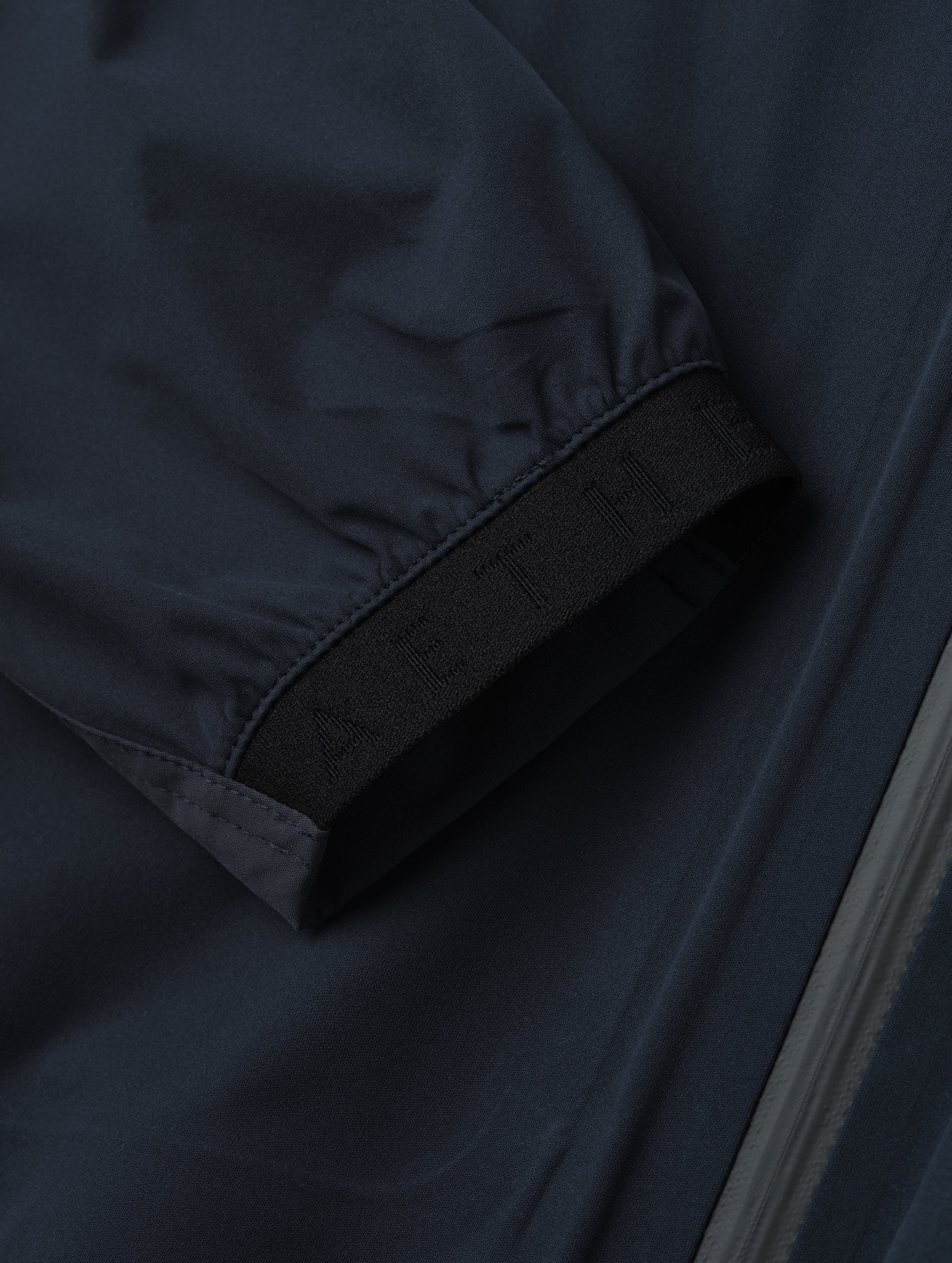 Closeup detailed view of one of the elasticated sleeve cuffs on the Frontier Pant in Total Eclipse dark blue from AETHER Apparel.