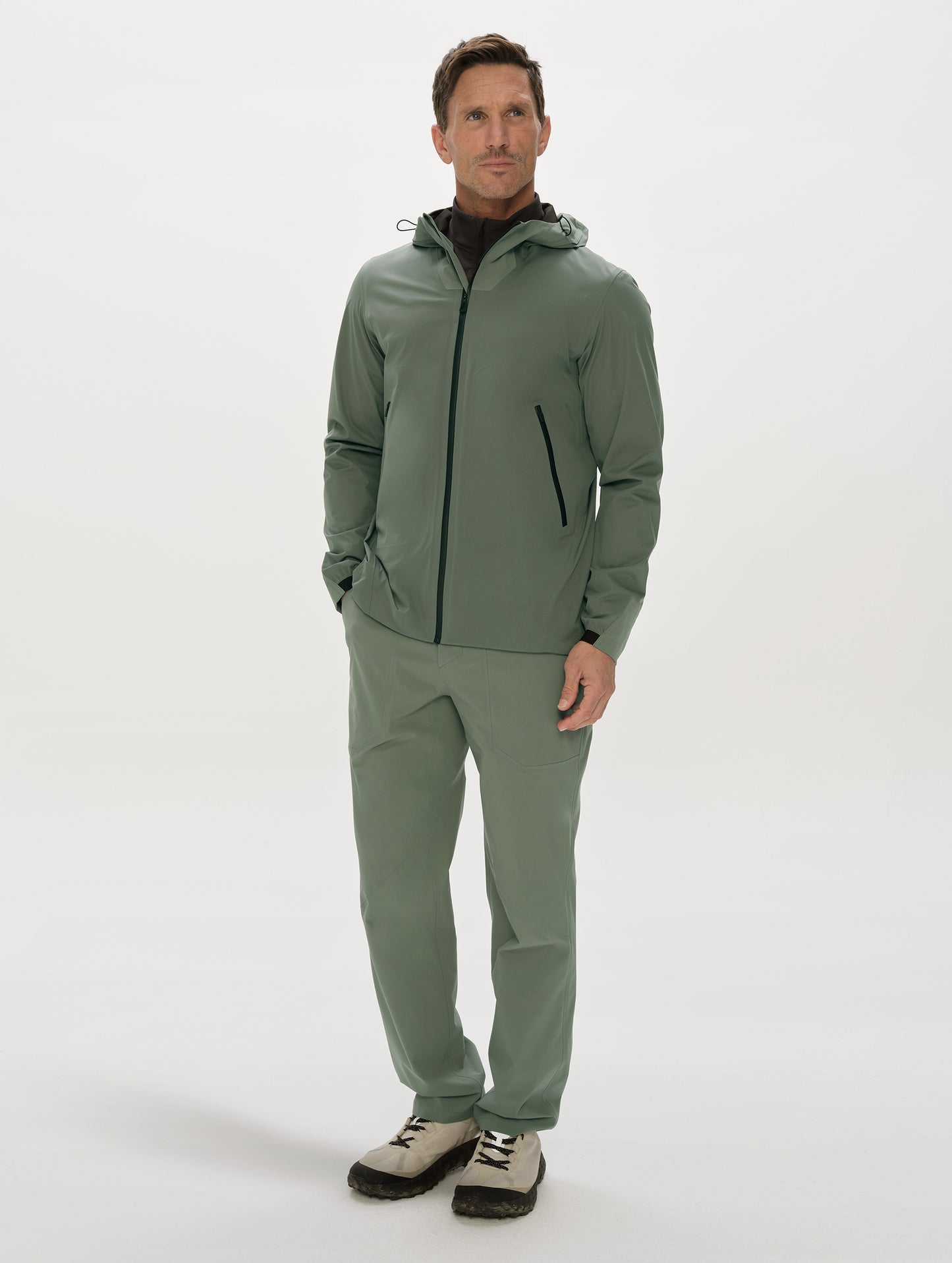 Front, full-body view of man wearing the Frontier Pant and Frontier Hooded Shell Jacket in Gunmetal  from AETHER Apparel.