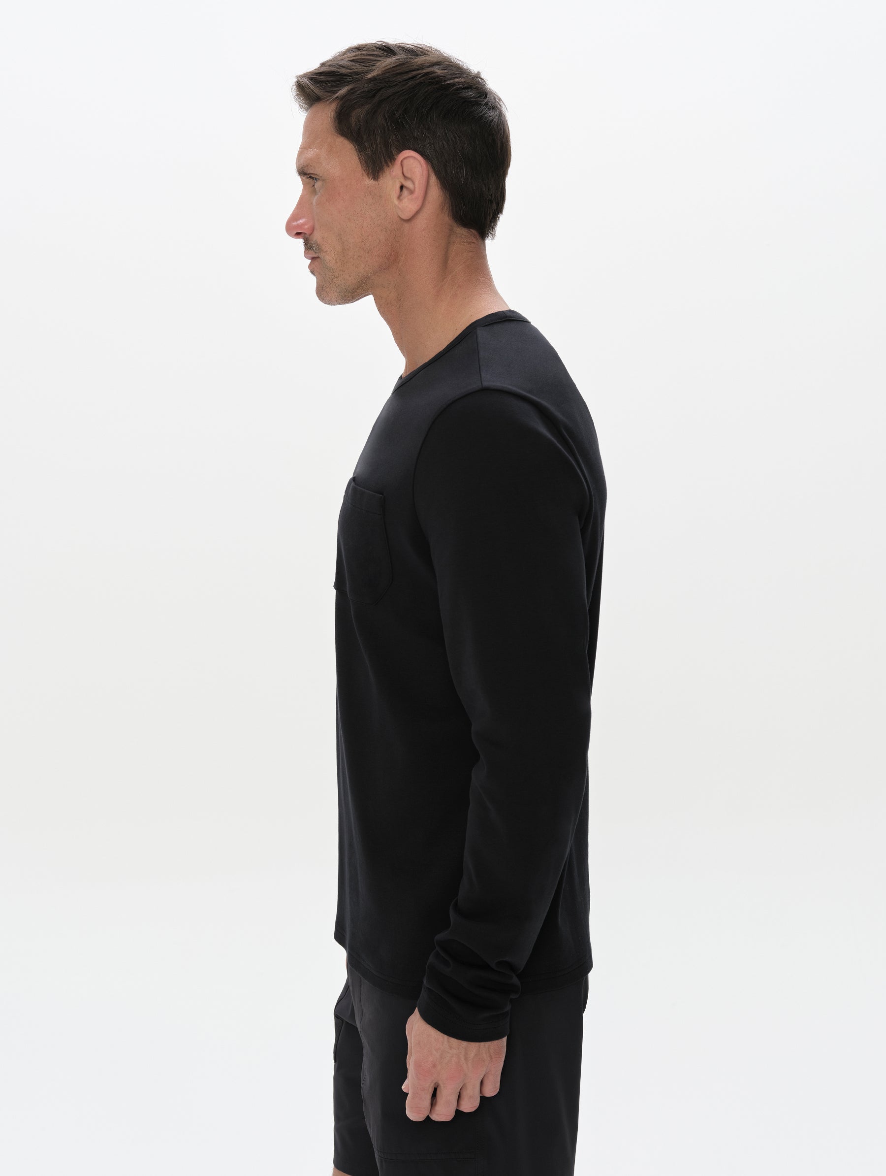 Side profile, upper-body view of man wearing the Harlow Premium Long-Sleeve Tee in Onyx Black from AETHER Apparel.