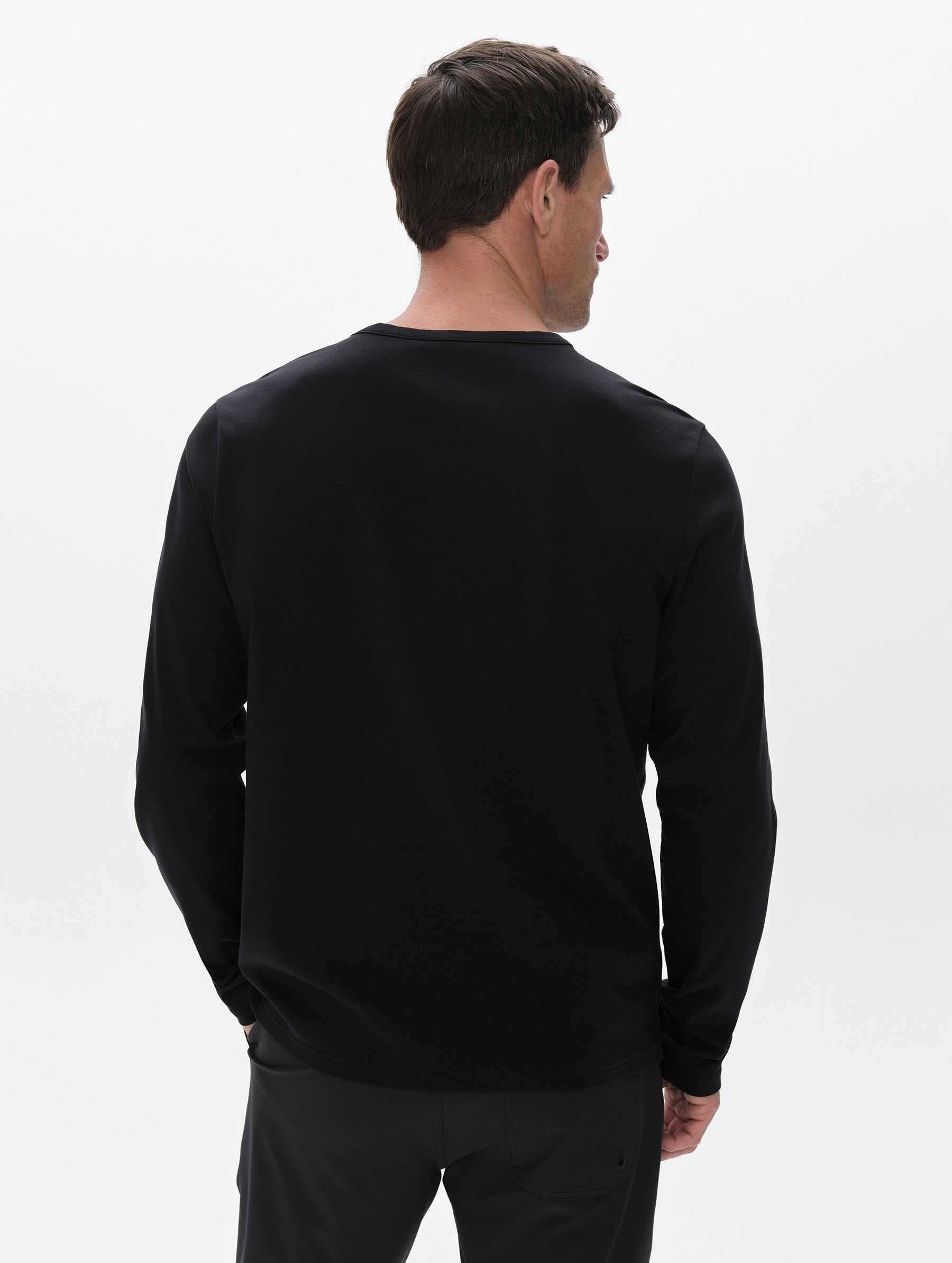 Rear, upper-body view of man wearing the Harlow Premium Long-Sleeve Tee in Onyx Black from AETHER Apparel.
