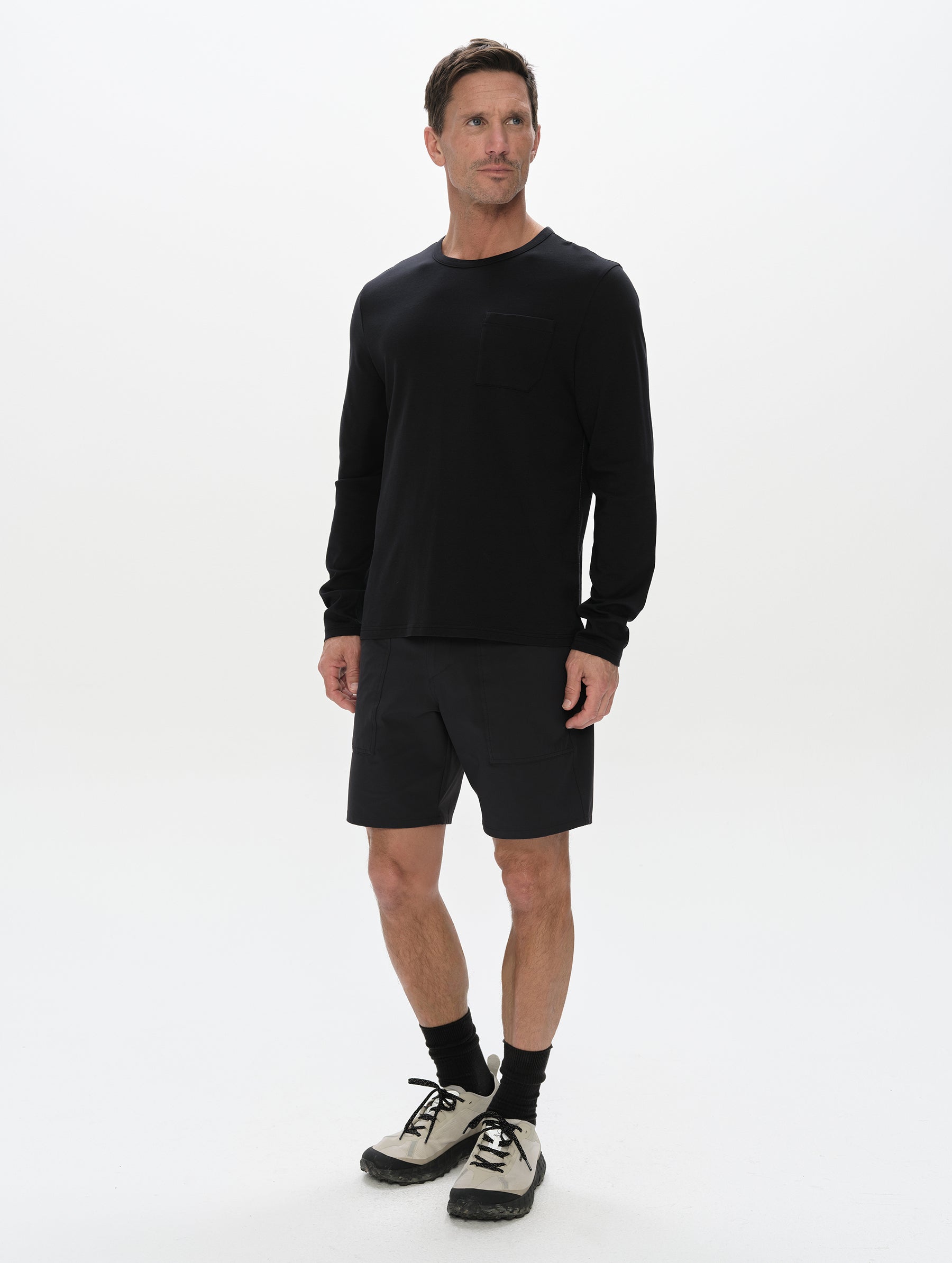 Front, full-body view of man wearing the Harlow Premium Long-Sleeve Tee in Onyx Black from AETHER Apparel.