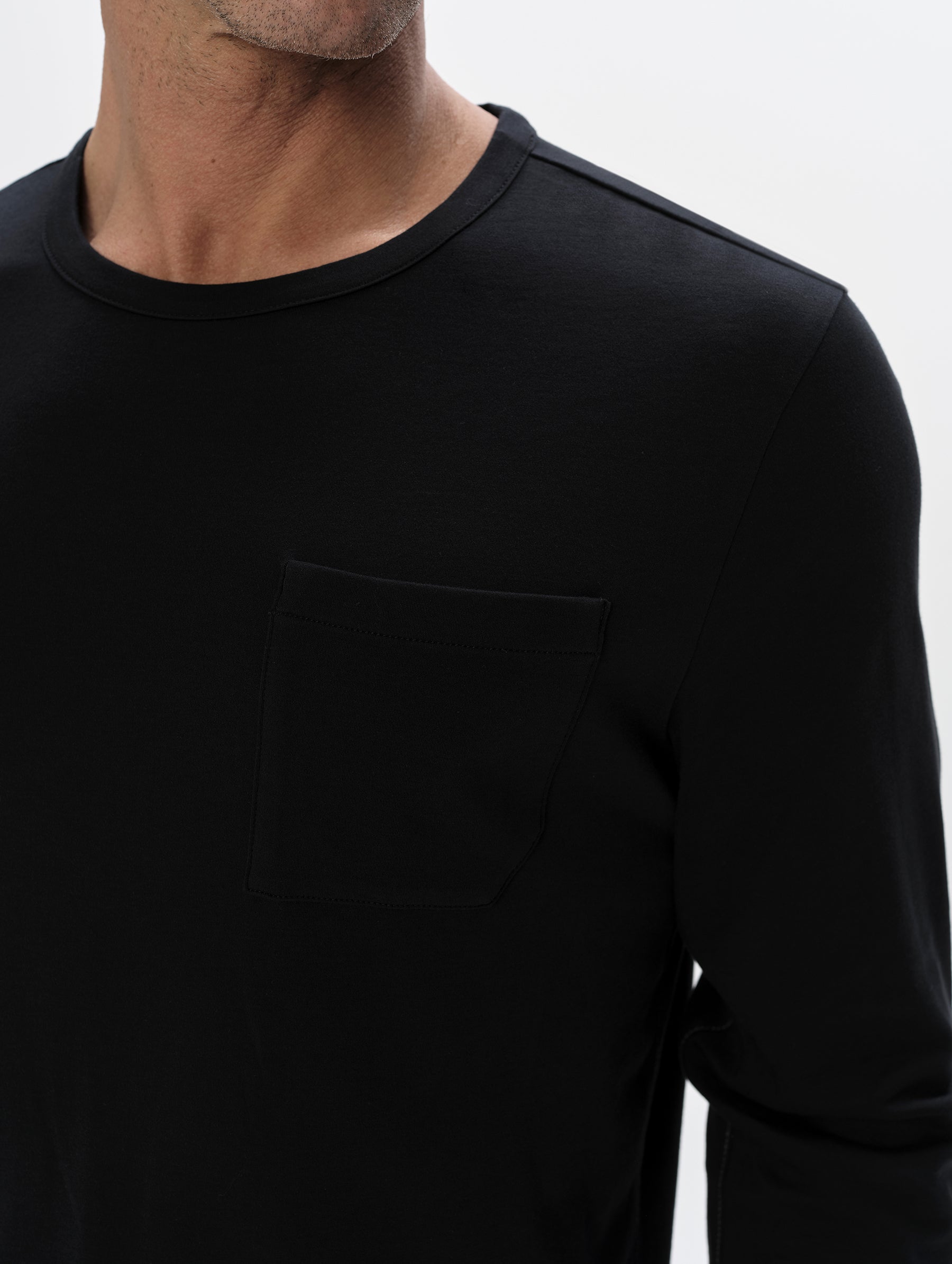 Closeup detailed view of the patch pocket and shoulder on the Harlow Premium Long-Sleeve Tee in Onyx Black from AETHER Apparel.