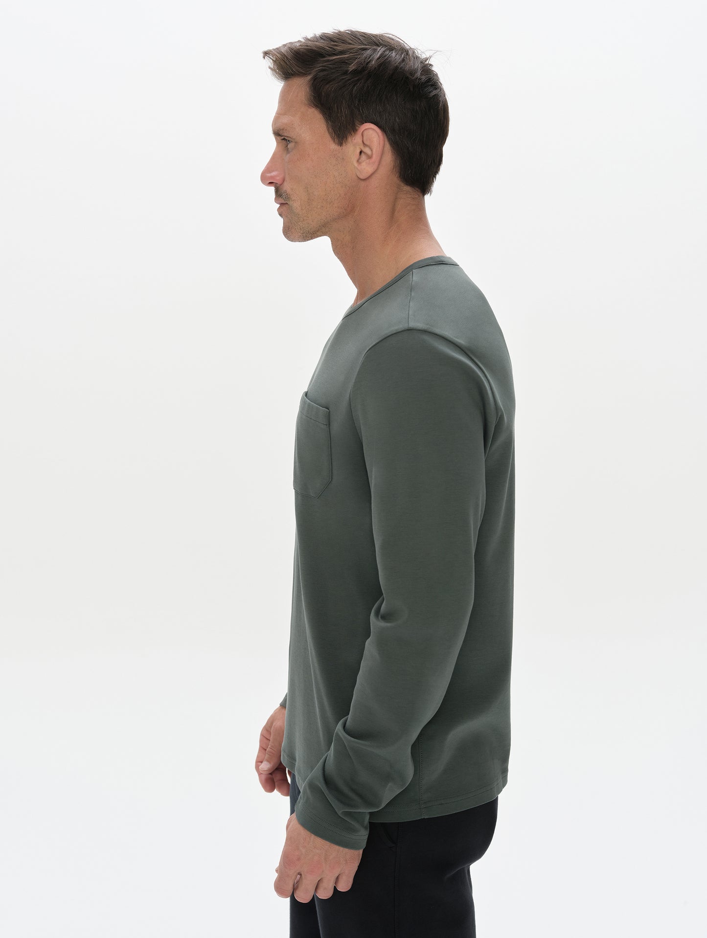 Side profile, upper-body view of man wearing Harlow Premium Long-Sleeve Tee in Saville Green  from AETHER Apparel.