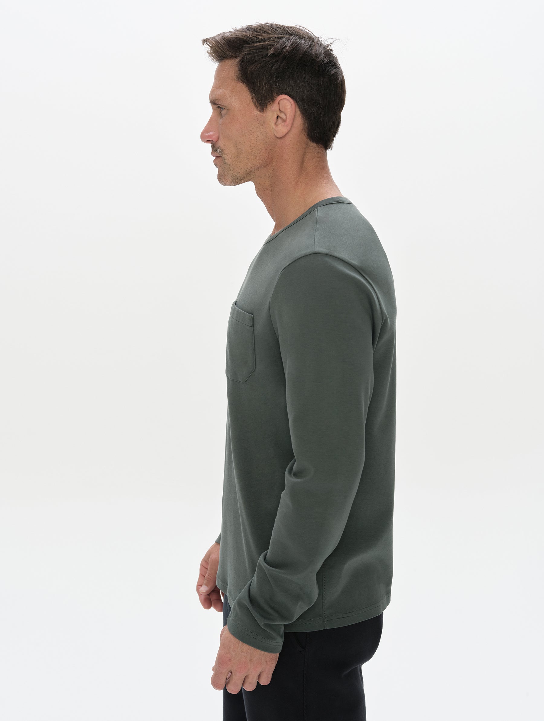 Side profile, upper-body view of man wearing Harlow Premium Long-Sleeve Tee in Saville Green  from AETHER Apparel.