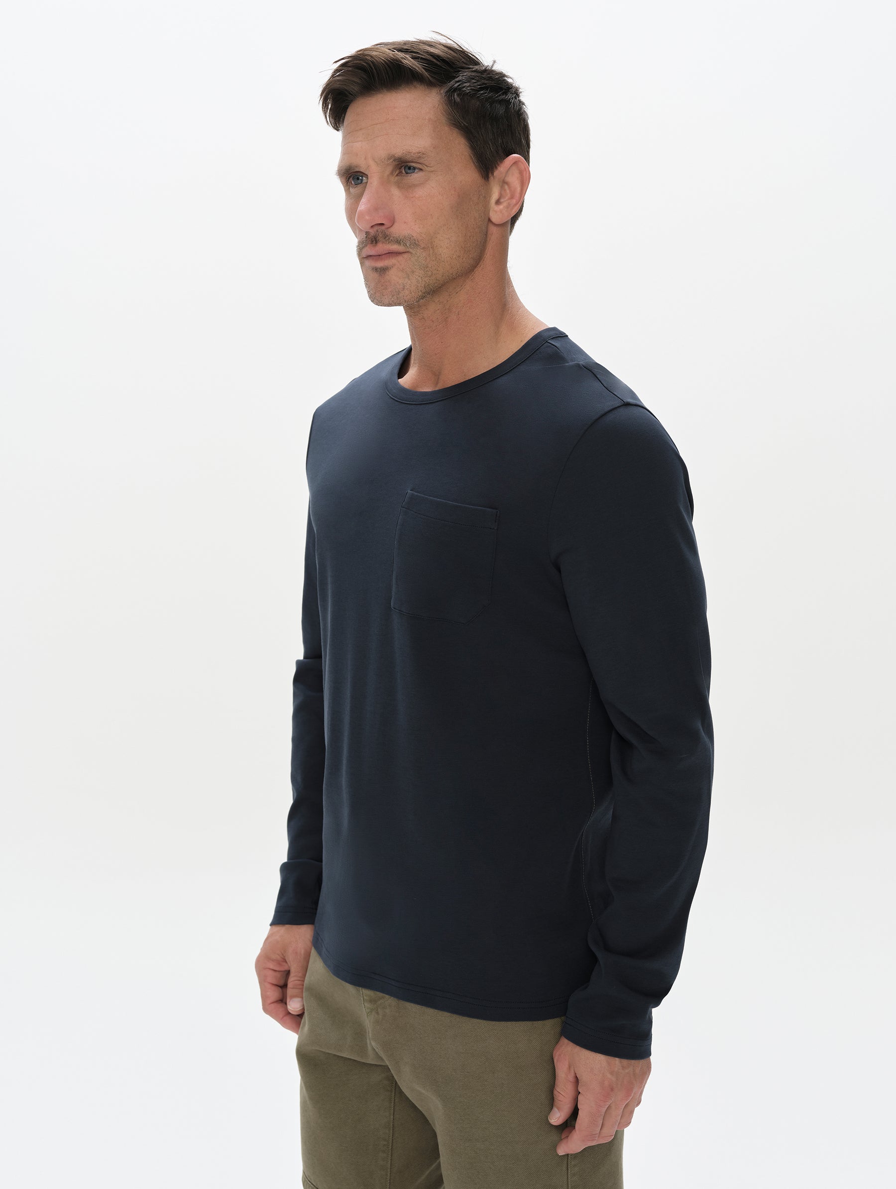 Front, 3/4, upper-body view of man wearing Harlow Premium Long-Sleeve Tee in Total Eclipse from AETHER Apparel.