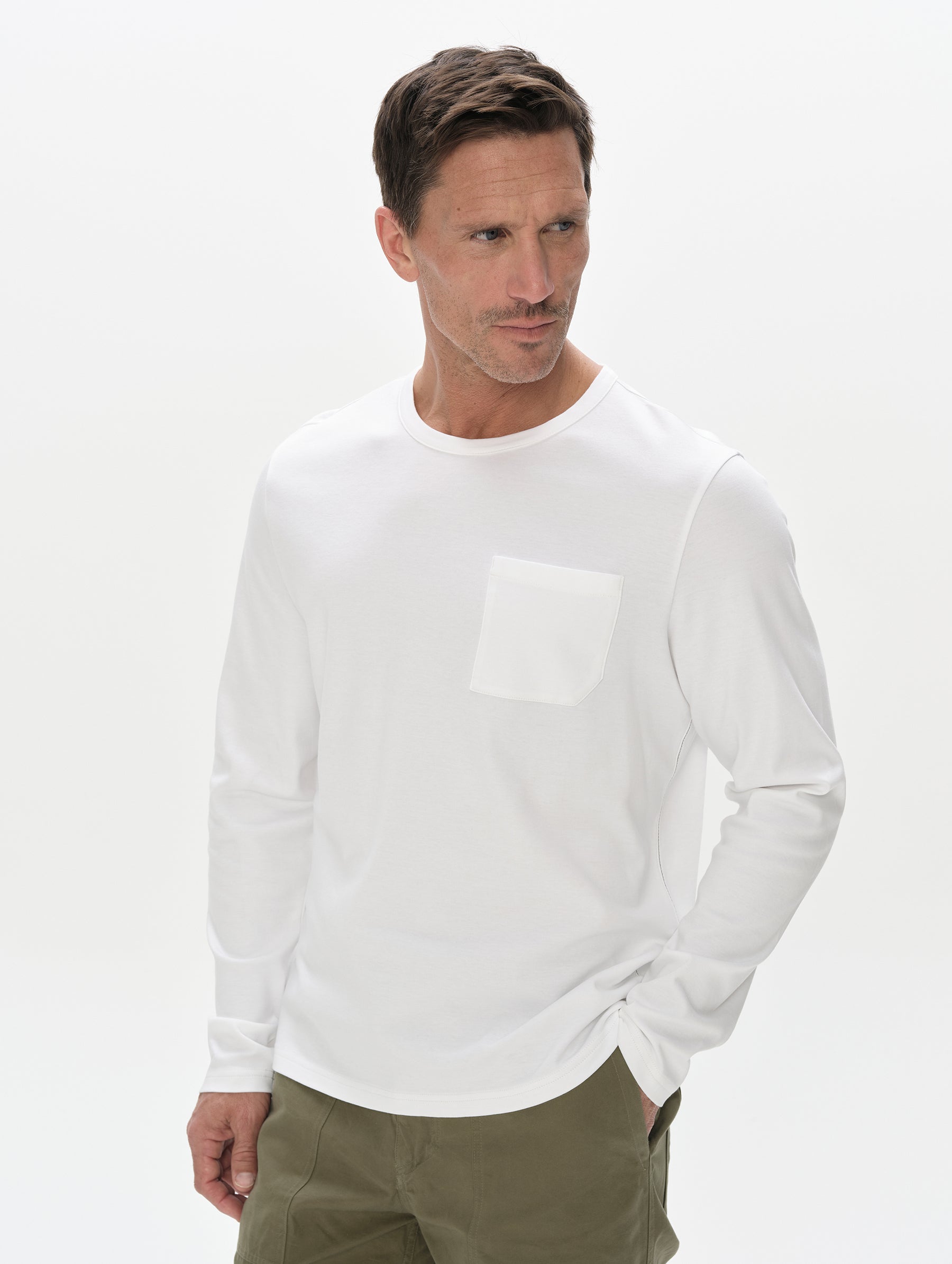 Front, upper-body view of man wearing Harlow Premium Long-Sleeve Tee in White from AETHER Apparel.
