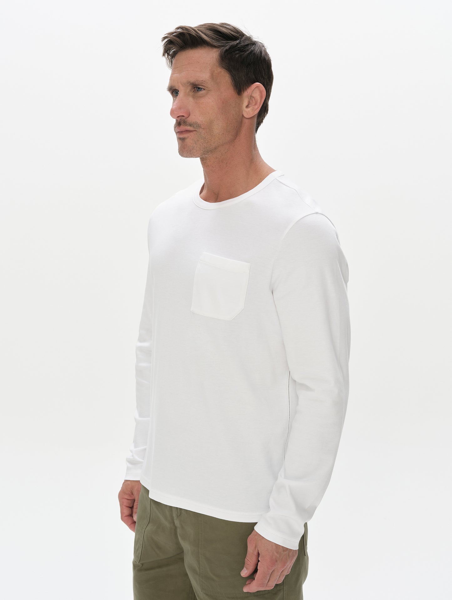 Front, 3/4, upper-body view of man wearing Harlow Premium Long-Sleeve Tee in White from AETHER Apparel.