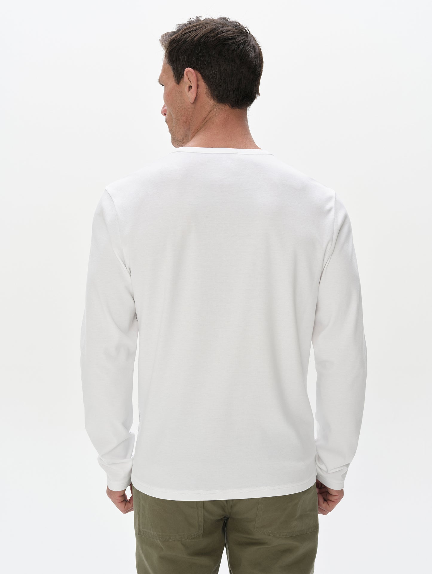 Rear, upper-body view of man wearing Harlow Premium Long-Sleeve Tee in White from AETHER Apparel.