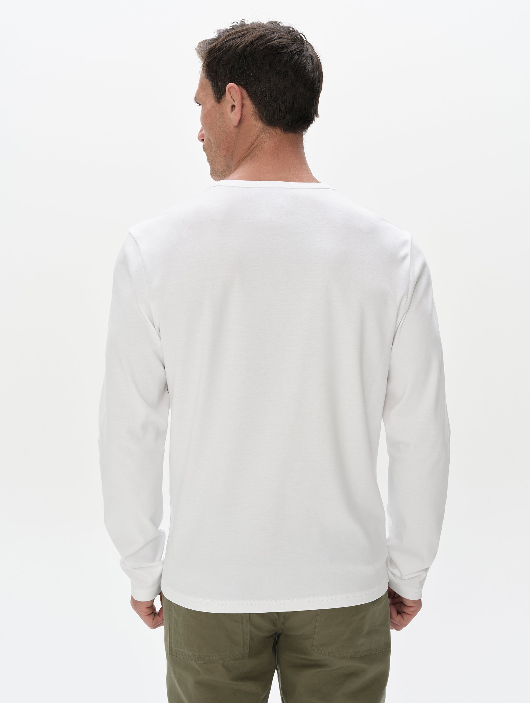 Rear, upper-body view of man wearing Harlow Premium Long-Sleeve Tee in White from AETHER Apparel.