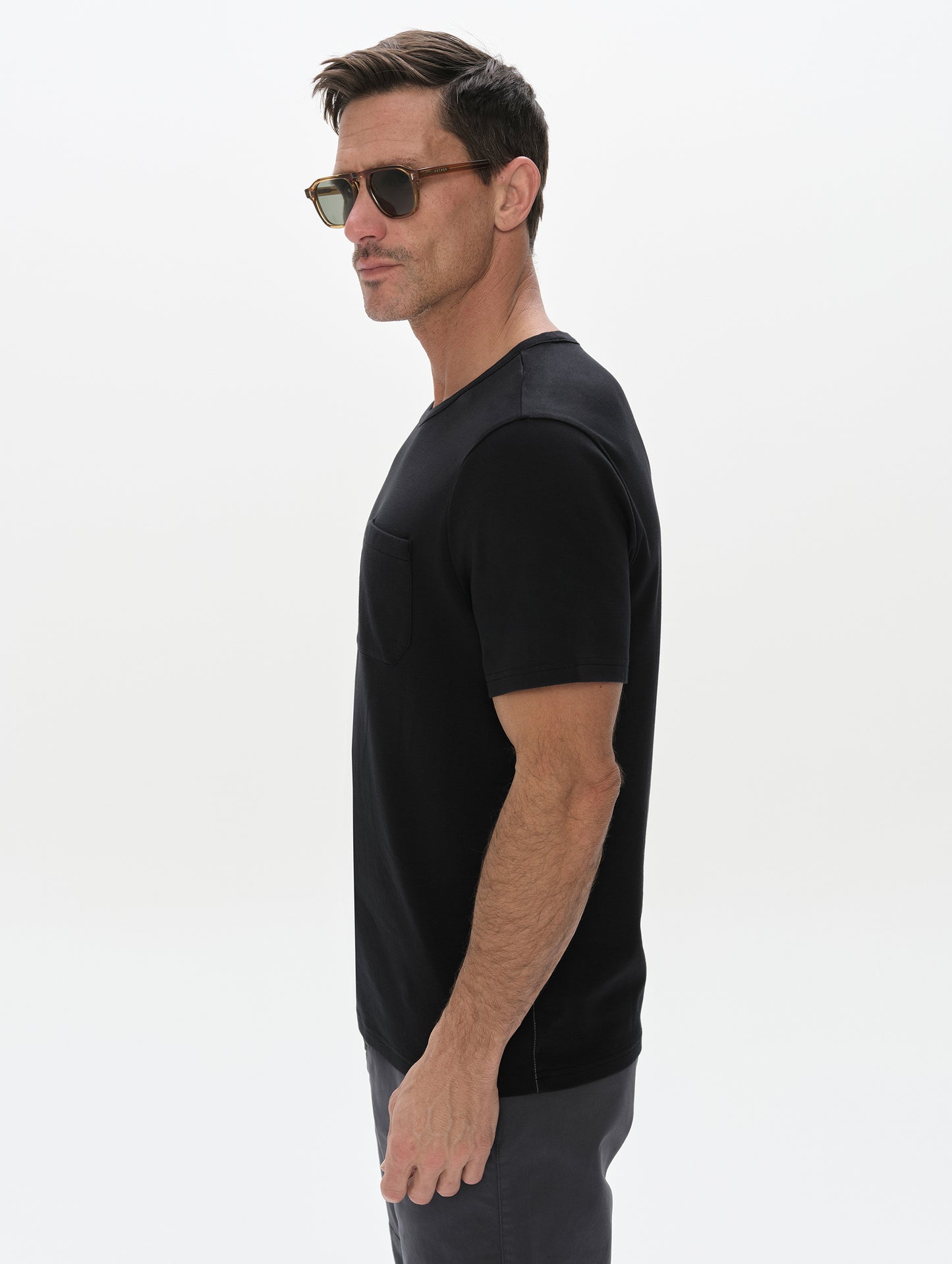 Side profile, upper-body view of man wearing the Harlow Premium Tee in Onyx Black from AETHER Apparel.