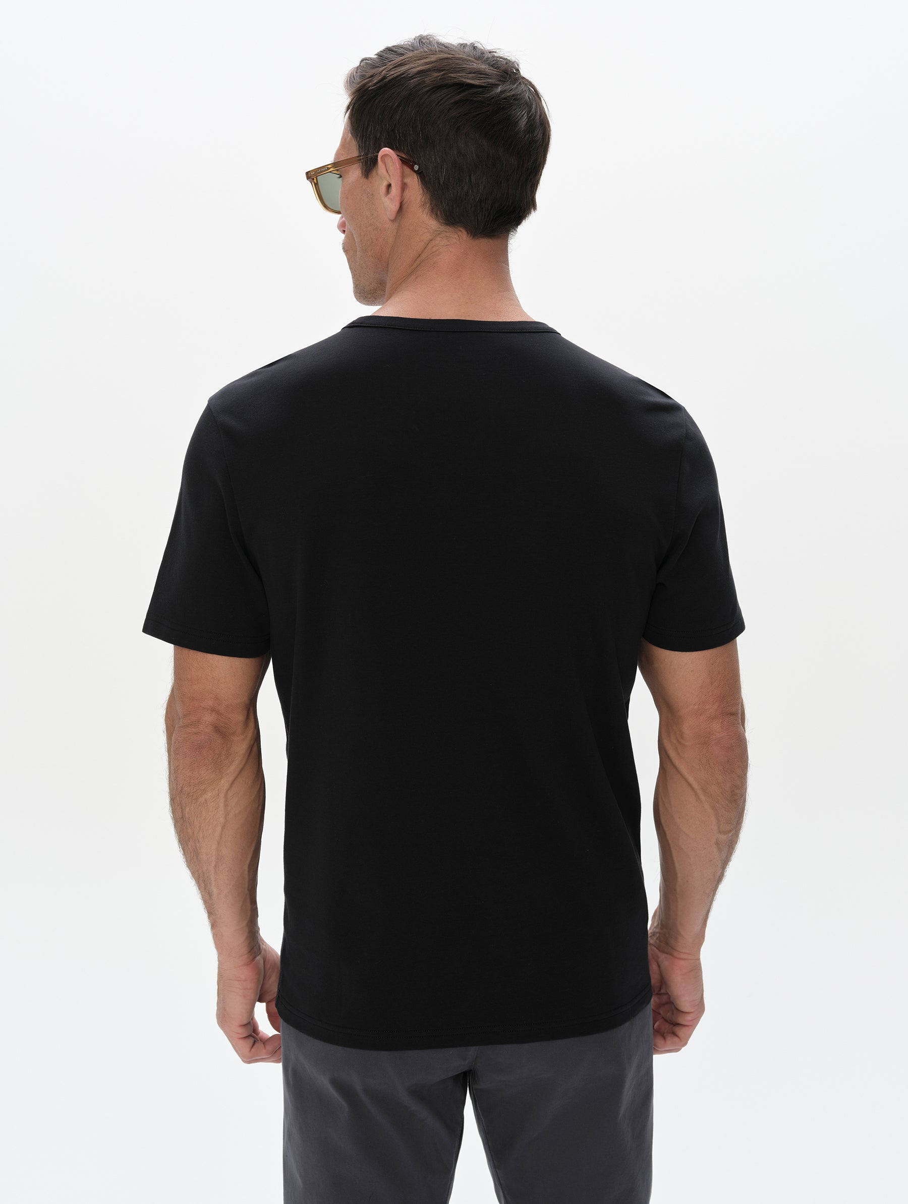 Rear, upper-body view of man wearing the Harlow Premium Tee in Onyx Black from AETHER Apparel.