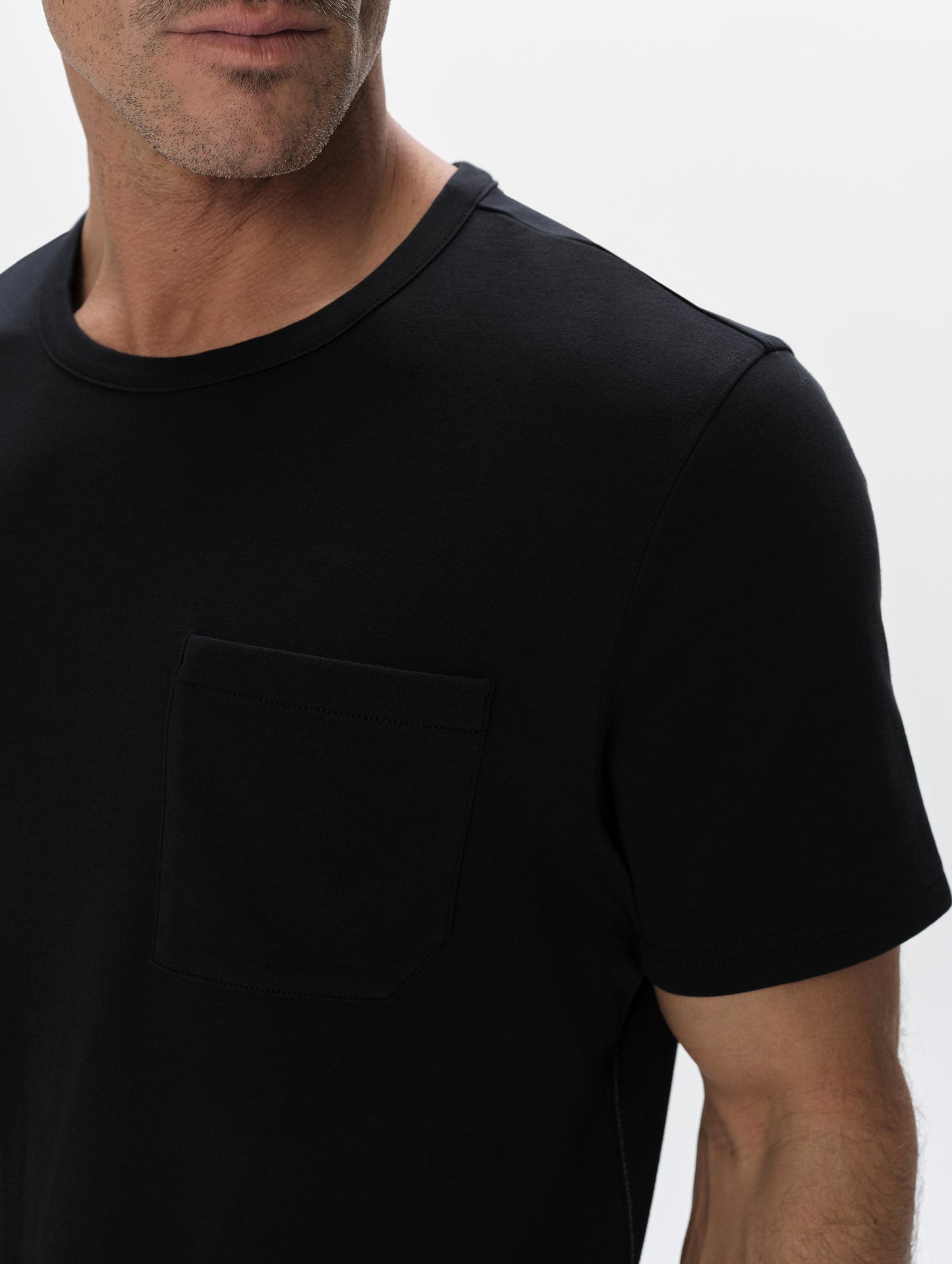 Closeup detailed view of the patch pocket and shoulder on the Harlow Premium Tee in Onyx Black from AETHER Apparel.