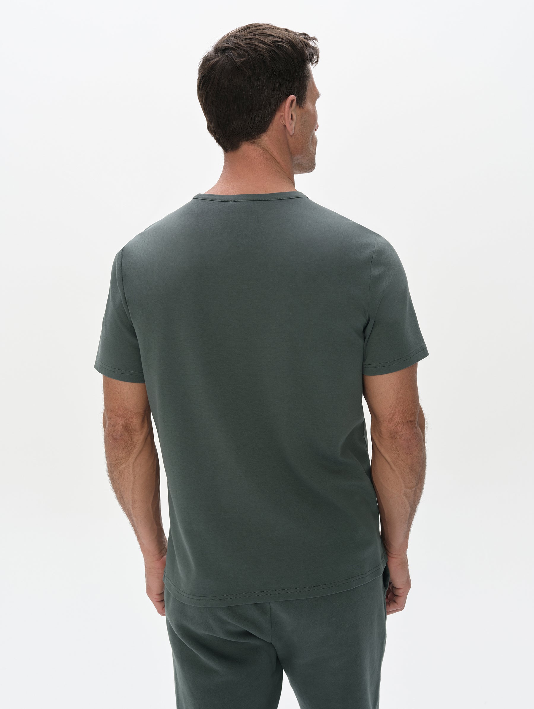 Rear, upper-body view of man wearing Harlow Premium Tee in Saville Green from AETHER Apparel.