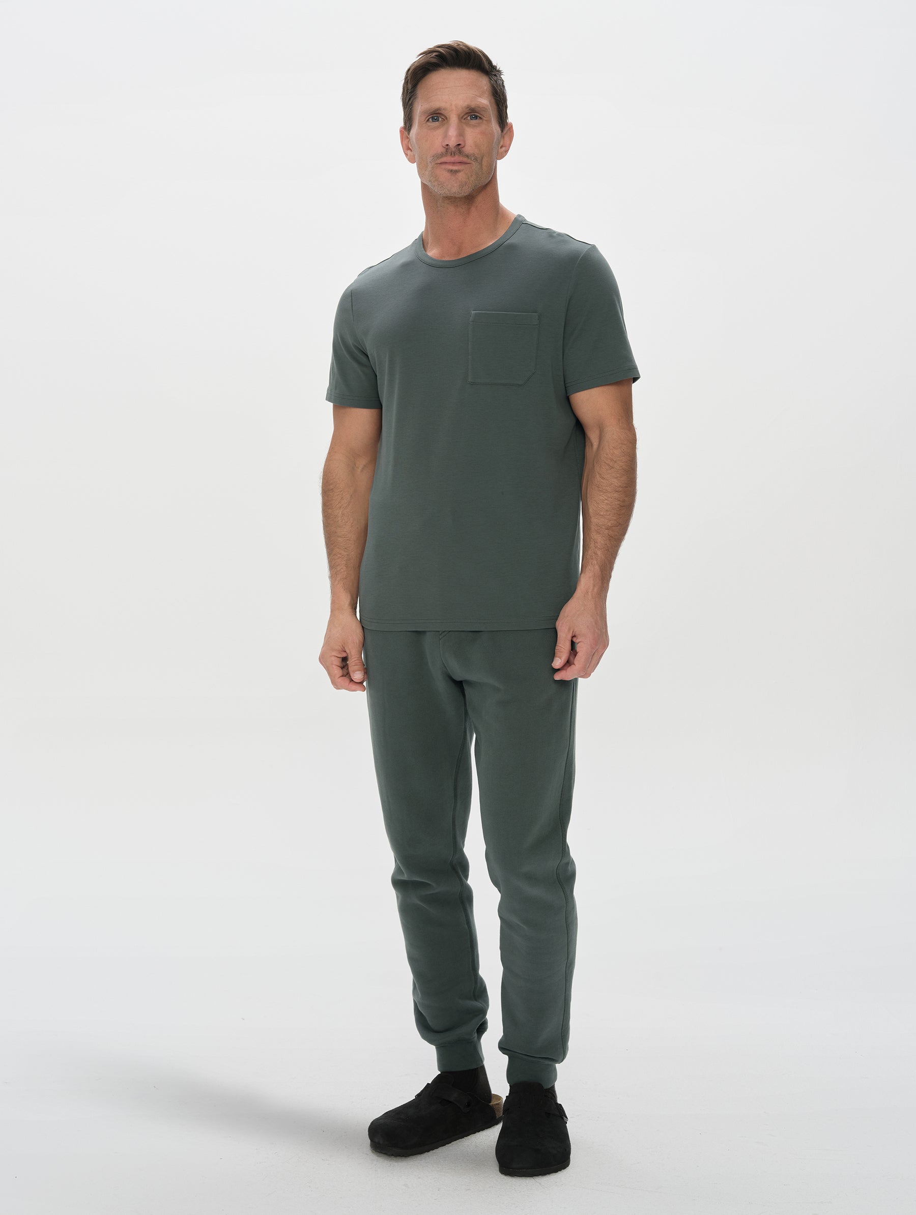 Front, full-body view of man wearing Harlow Premium Tee in Saville Green from AETHER Apparel.