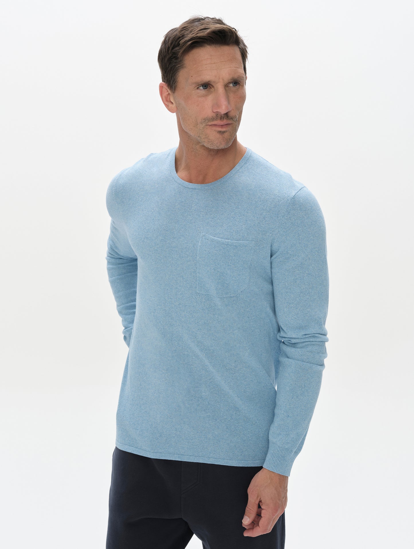 Front, upper-body view of the man wearing the Aero Crewneck Sweater 2.0 in Cloud Blue from AETHER Apparel.